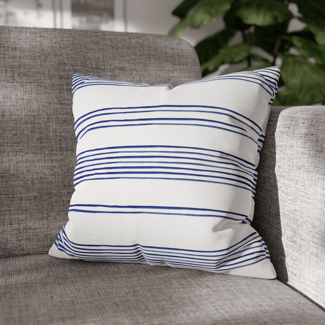 Hamptons Striped Pillow on a couch with blue and white stripes for coastal home decor.