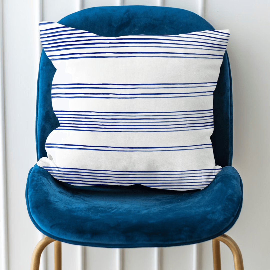 Hamptons Striped Pillow on a blue chair showcasing blue and white stripes, adding coastal charm to home decor.
