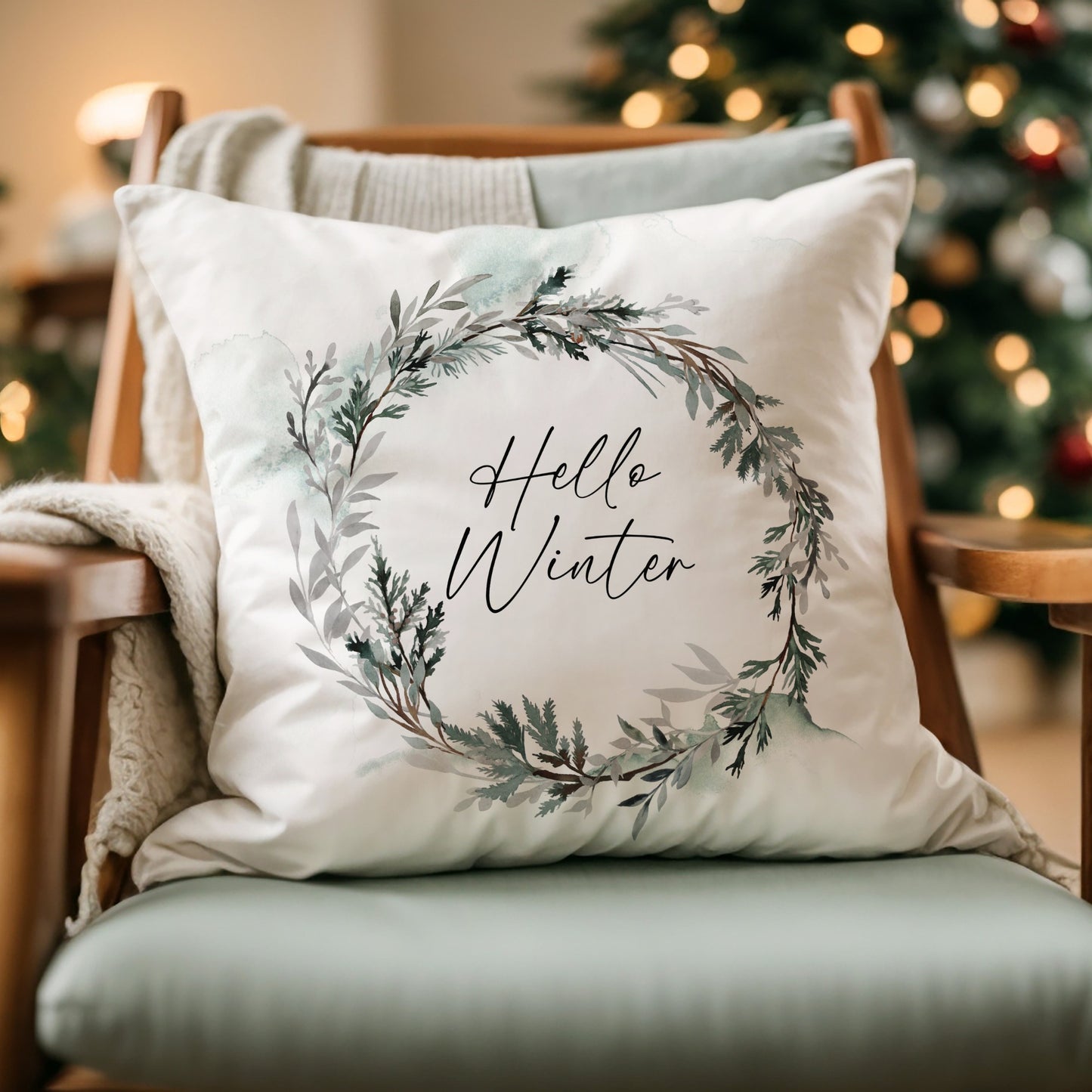 Hello Winter pillow with watercolor wreath on cozy chair – elegant Christmas pillow for seasonal home decor