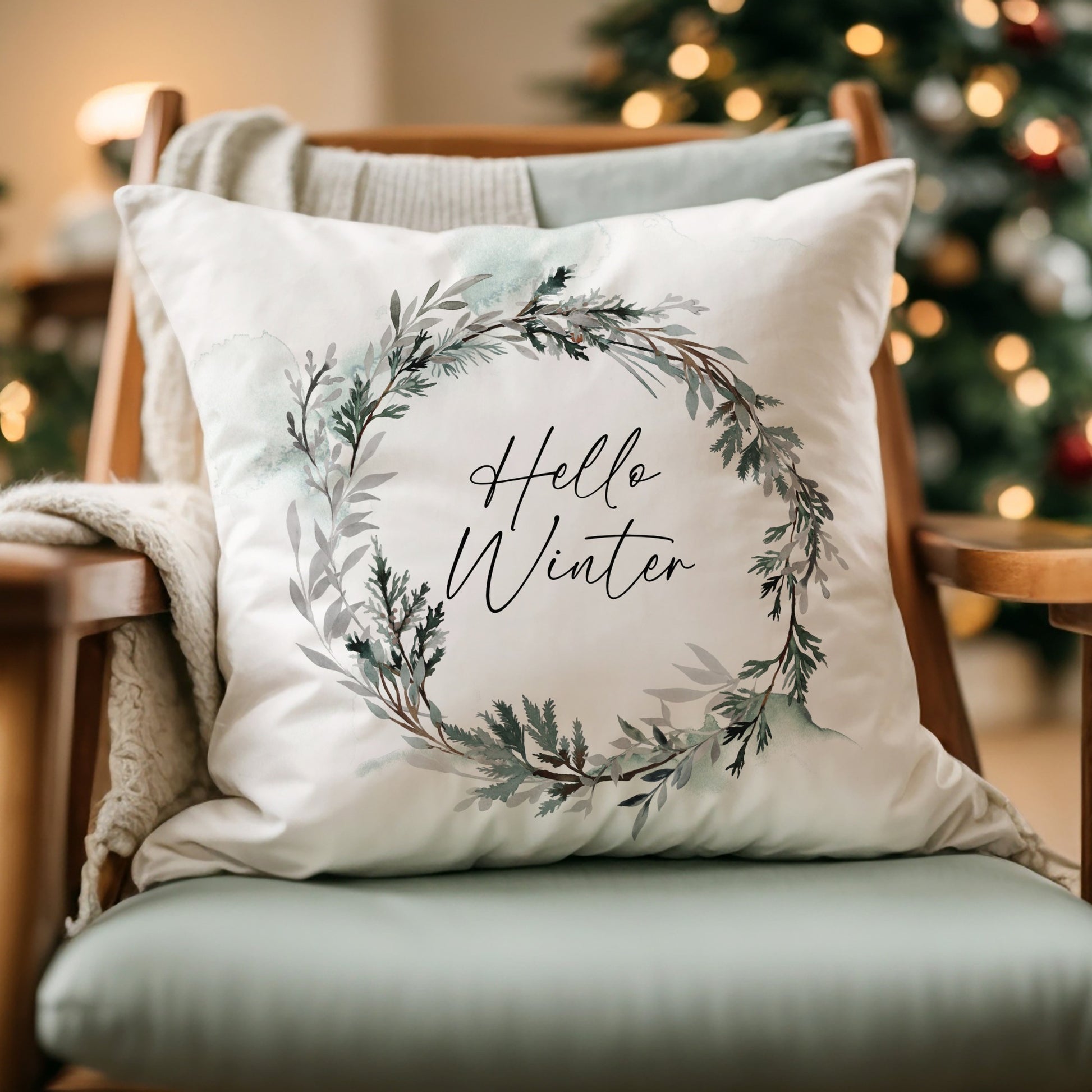 Hello Winter pillow with watercolor wreath on cozy chair – elegant Christmas pillow for seasonal home decor