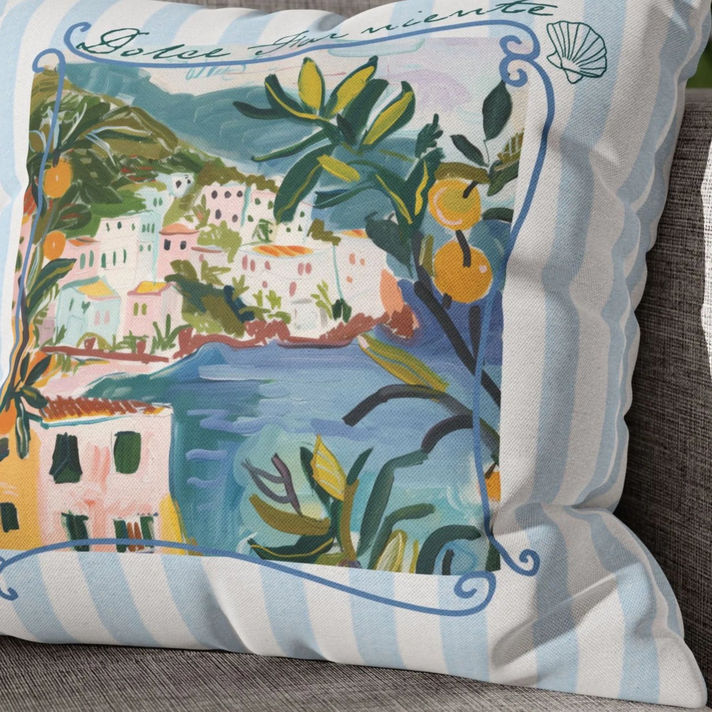 Close-up of “Dolce Far Niente” pillow with Amalfi Coast and lemon print on light blue striped fabric.