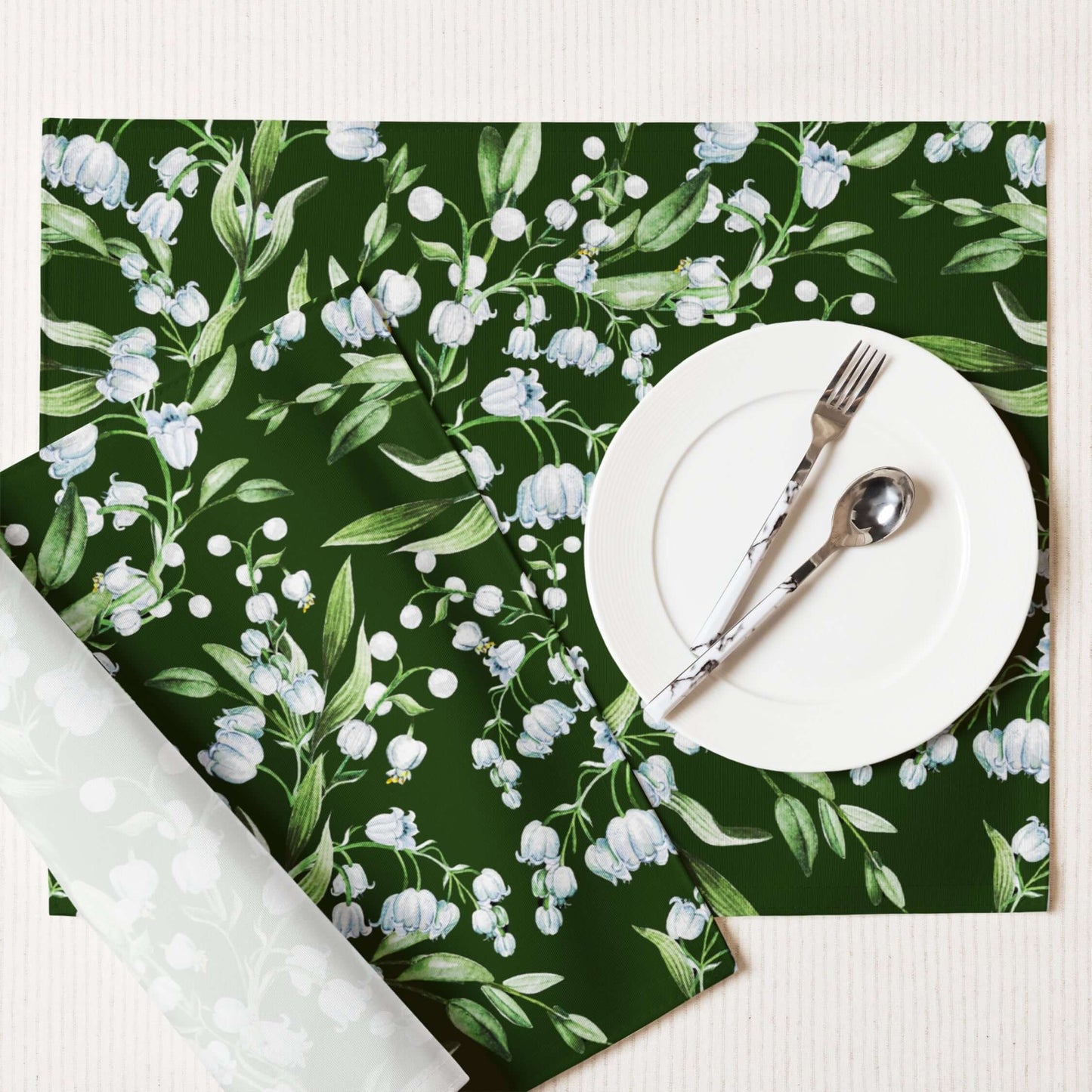 Lily Of The Valley PLACEMAT Set displayed on a table with a white plate and silver cutlery, featuring dark green floral design.
