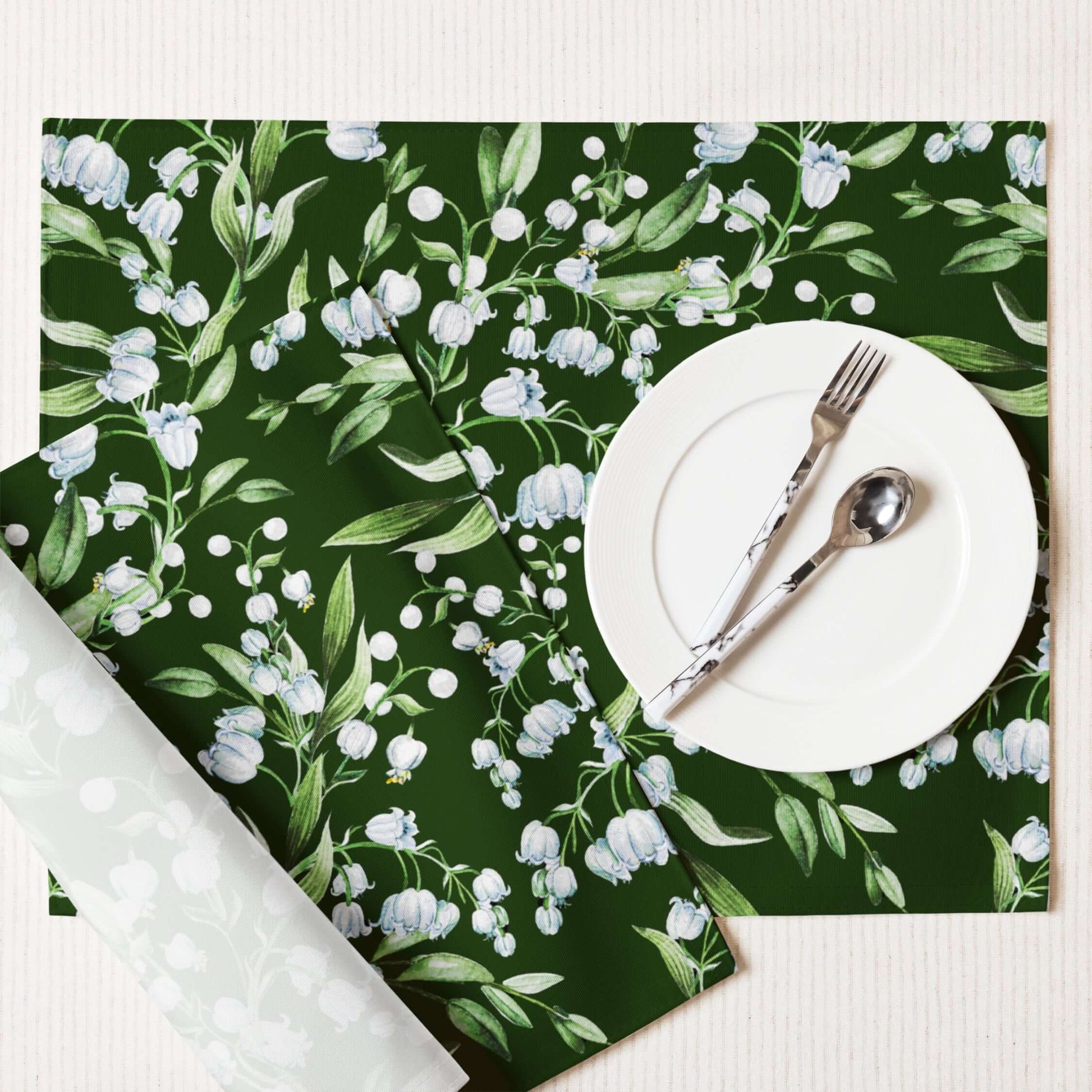 Lily Of The Valley PLACEMAT Set displayed on a table with a white plate and silver cutlery, featuring dark green floral design.