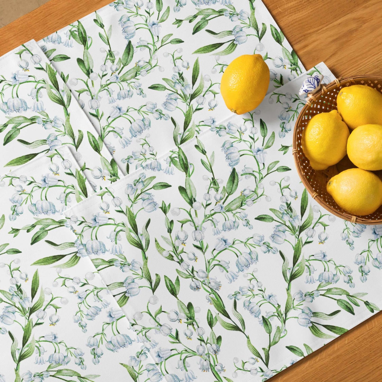 Lily Of The Valley PLACEMAT Set displayed on a wooden table with lemons, showcasing its floral design and elegant charm.
