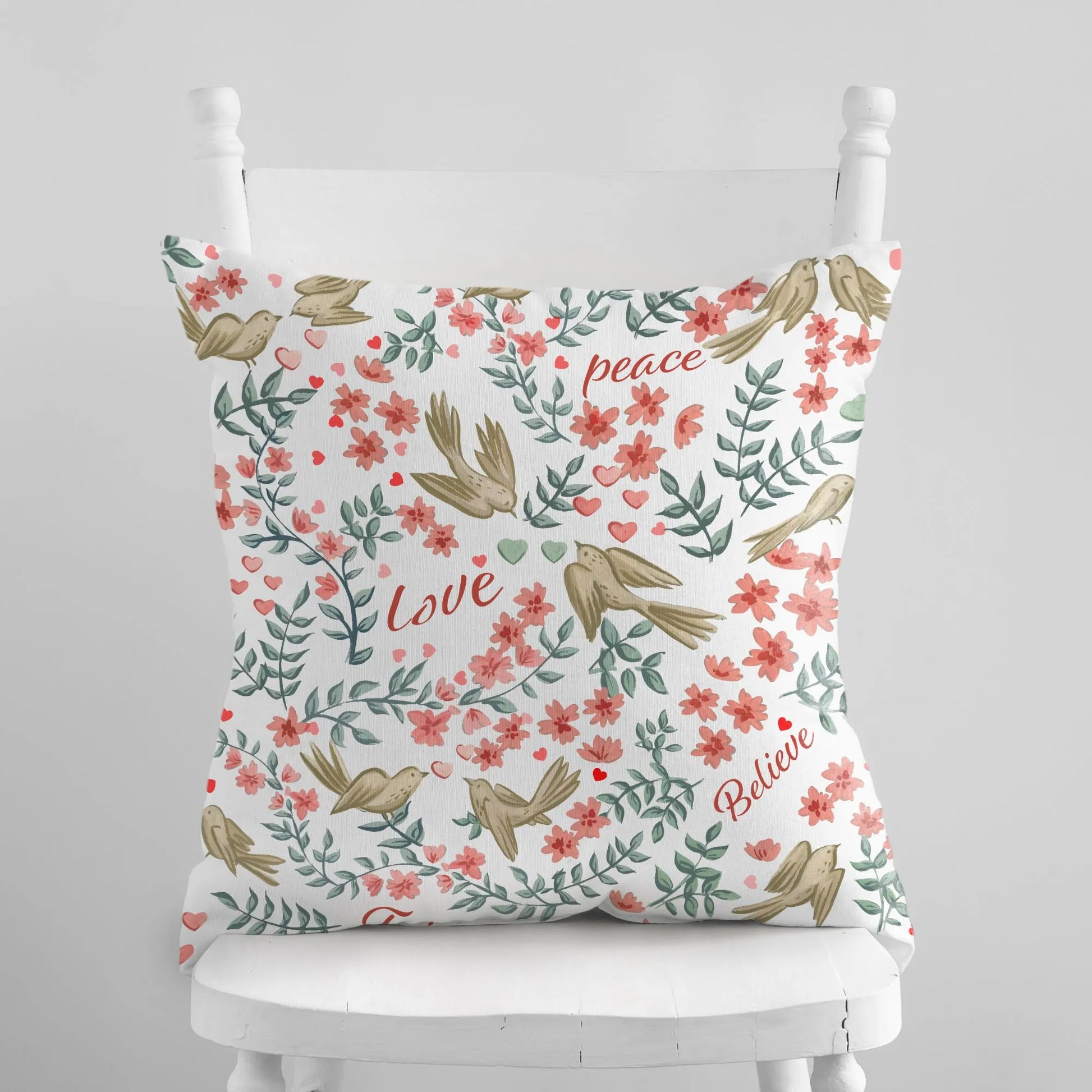 Decorative "Hope Peace Love Believe" Love Birds Valentine Pillow Cover with bird and floral design on a white wooden chair.