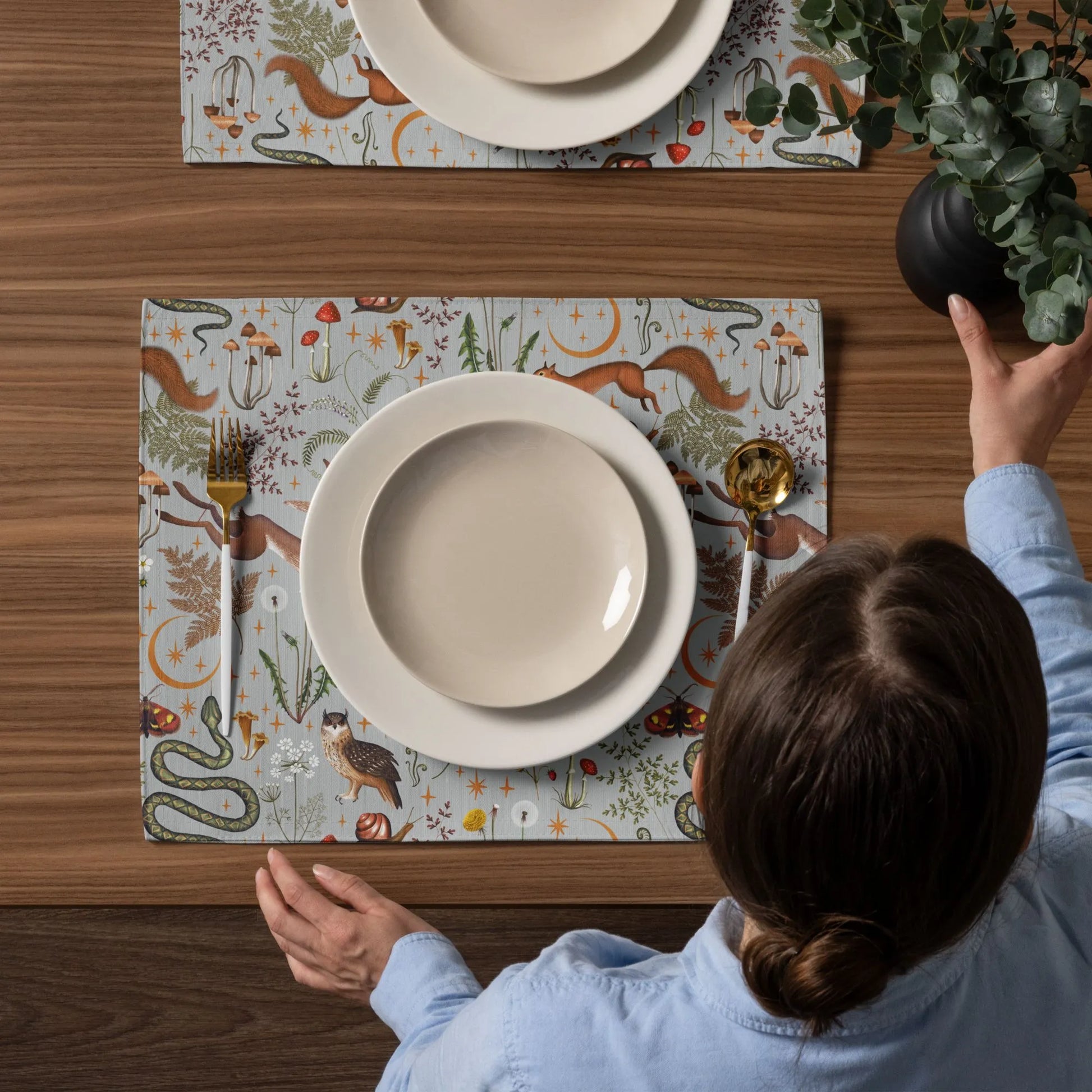 woman setting up dining table with Magic Forest PLACEMATS from Blue Water Songs