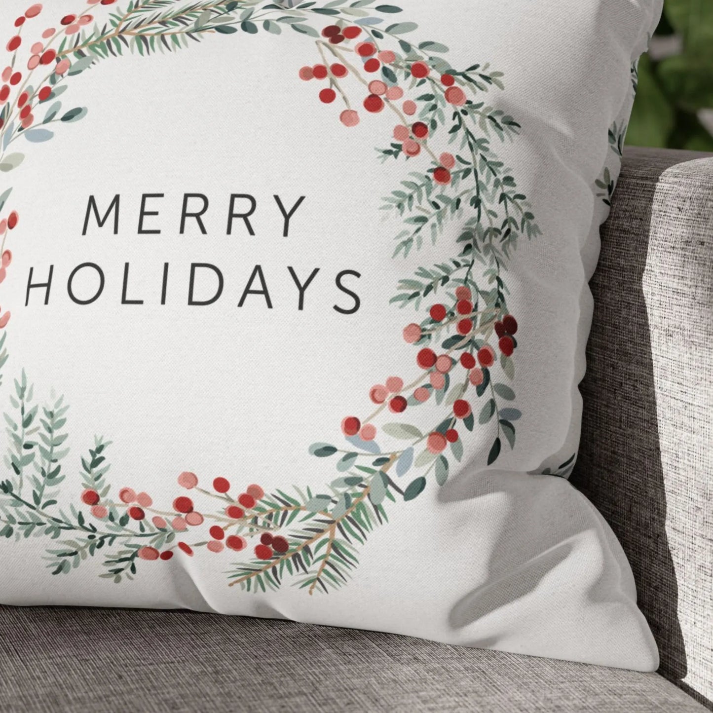 Close-up of white Merry Holiday pillow with pine wreath and red berries – festive nature-inspired Christmas accent