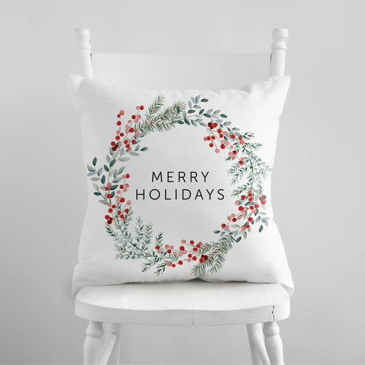 Merry Holiday Christmas wreath pillow with watercolor pine and red berries on white chair – festive seasonal decor