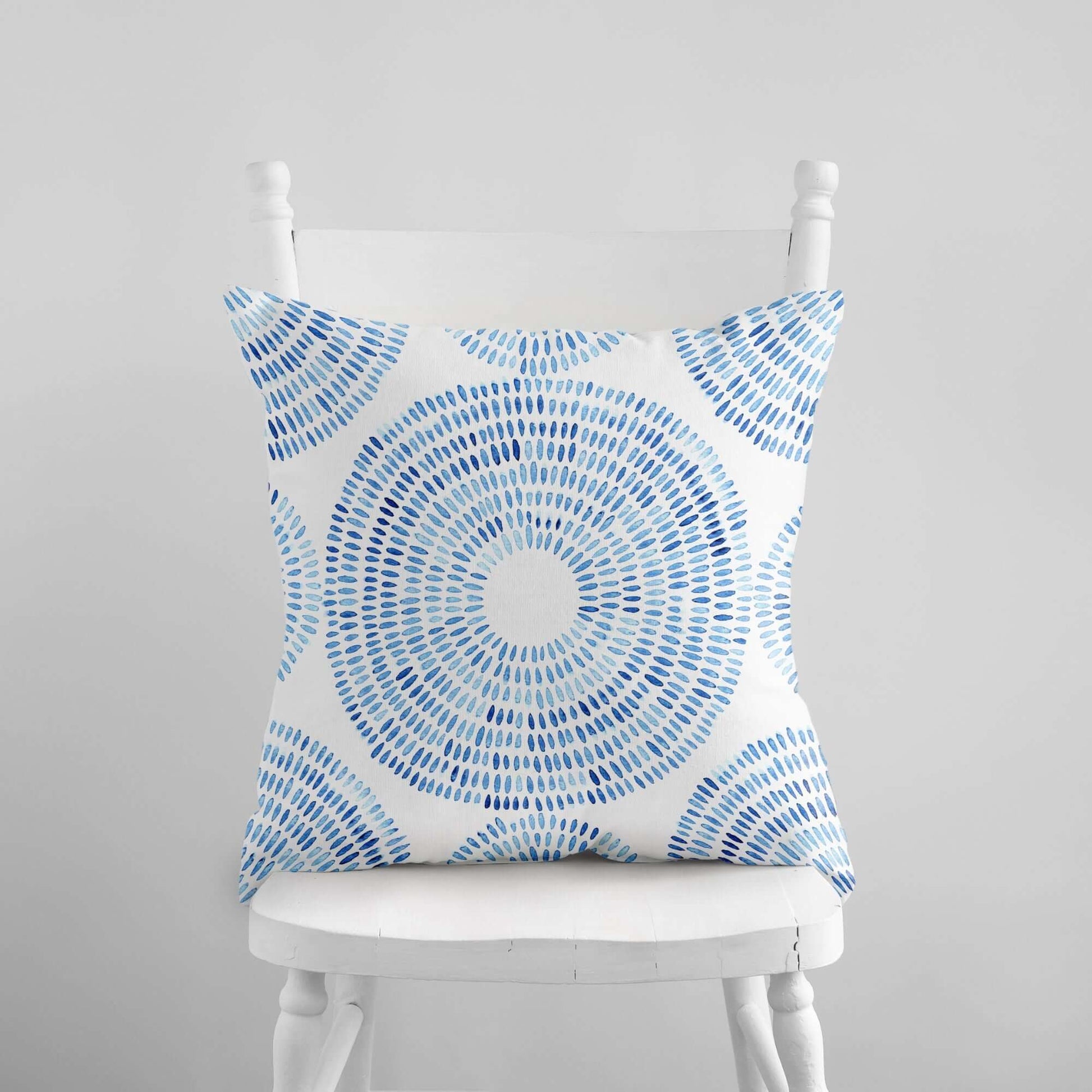 Blue watercolor coastal pillow cover on white chair — summer coastal home decor