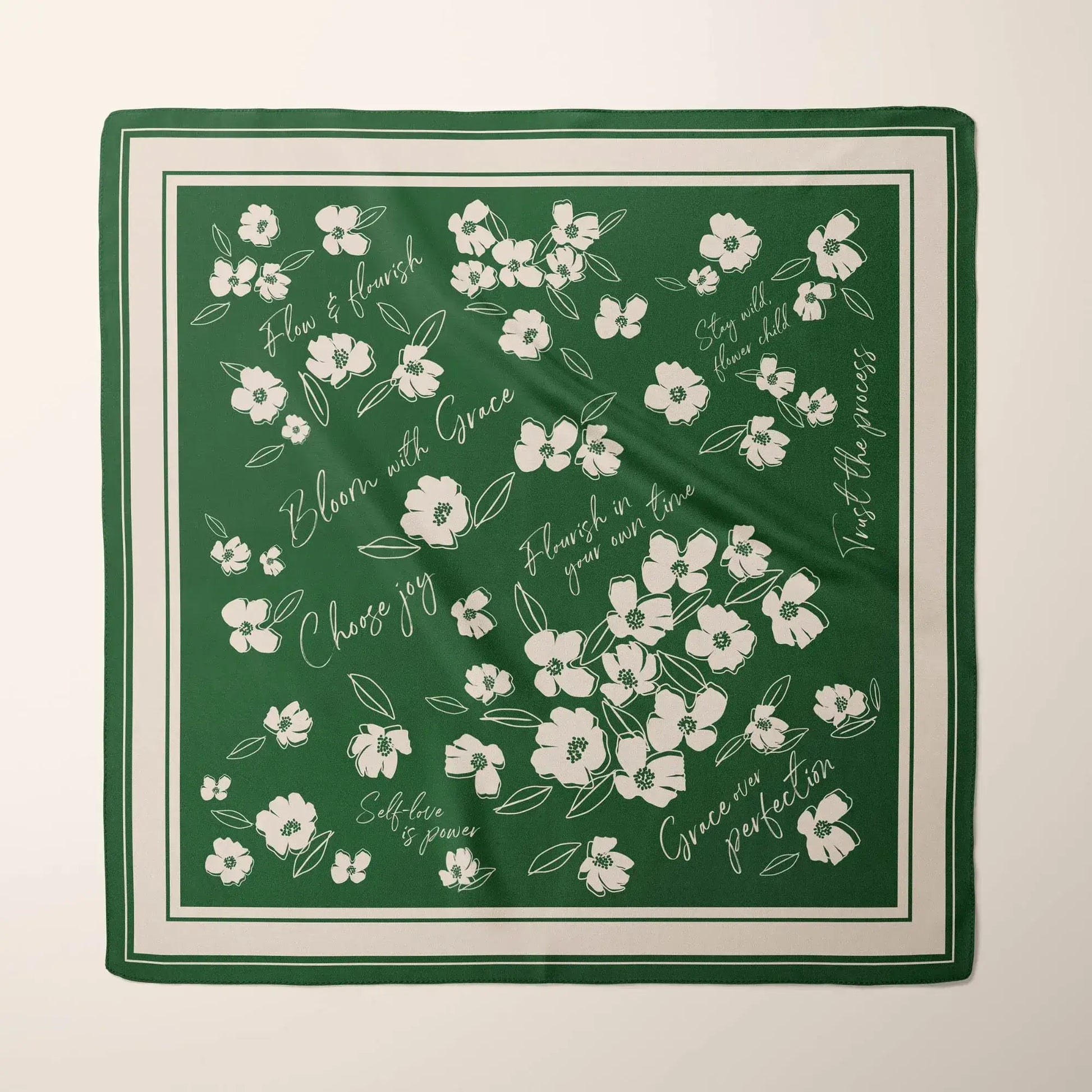 Emerald green silk scarf with white wildflower illustrations and inspirational phrases like "Bloom with Grace