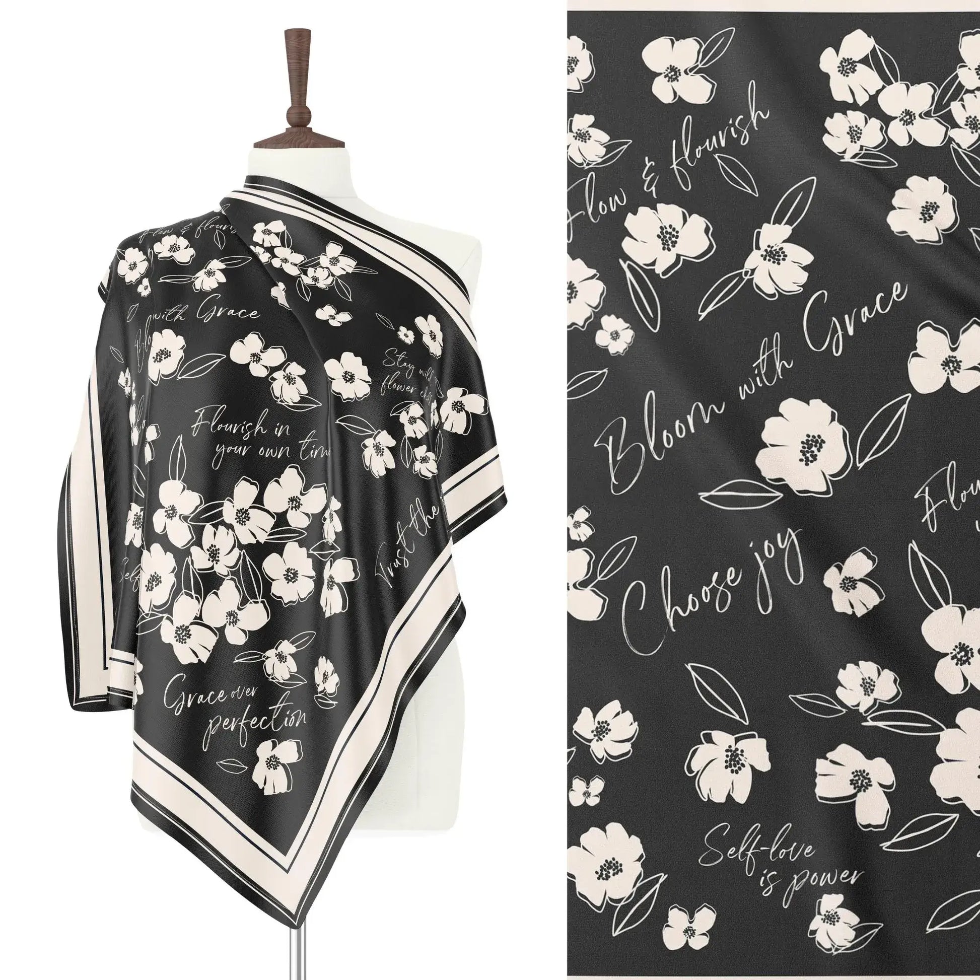 Black silk scarf draped on a mannequin, showcasing white wildflowers and inspirational words like "Bloom with Grace". Design close-up shown.