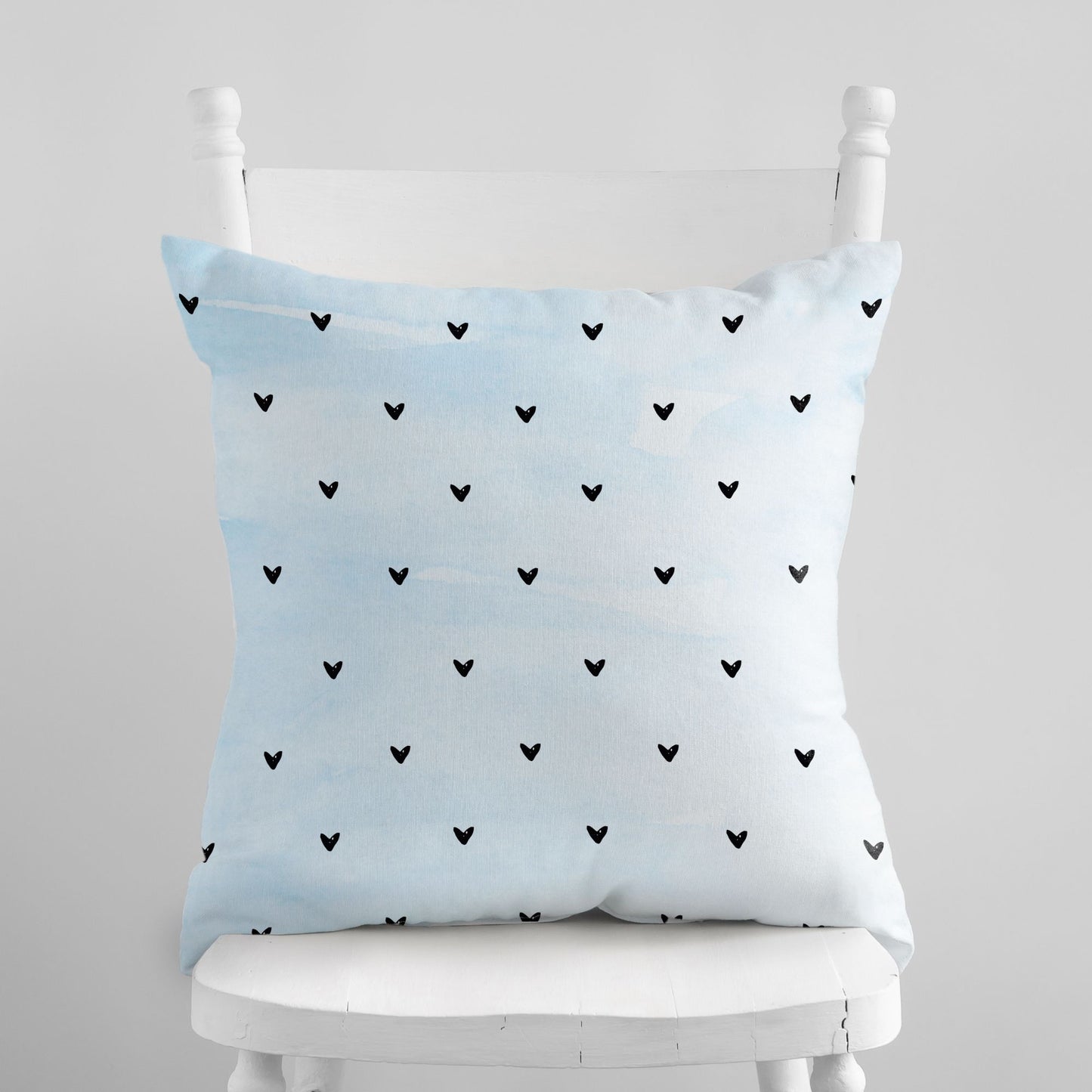 Minimalist Hearts Valentine Pillow with scattered black hearts on a white chair, Blue Water Songs brand.