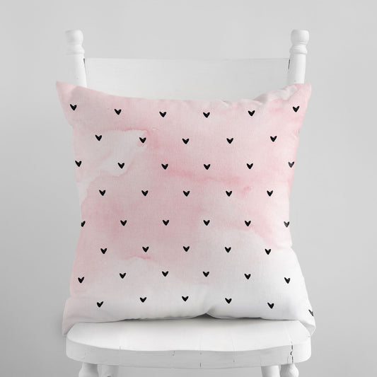 Minimalist Hearts Valentine Pillow by Blue Water Songs on white chair. Pink and white with scattered black hearts.