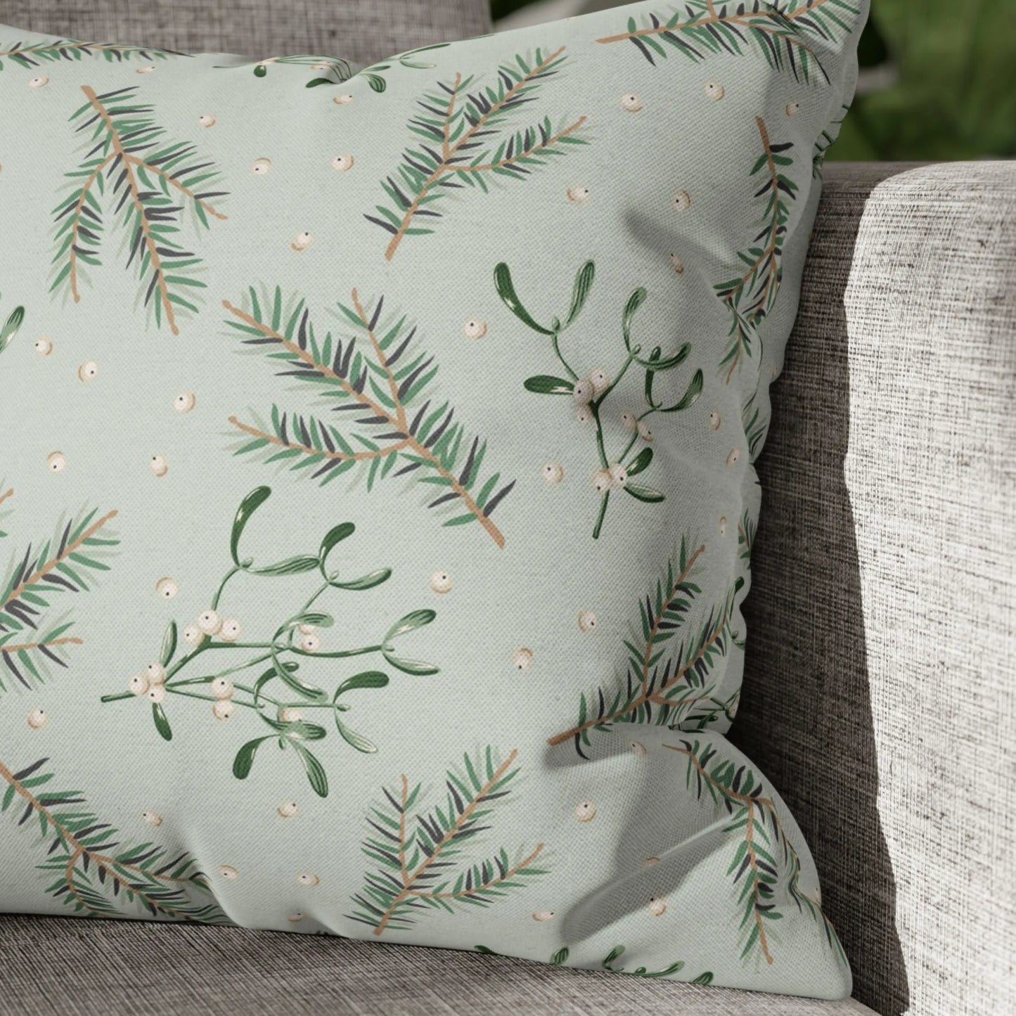 Close-up of mistletoe Christmas pillow with pine branches and white berries on green fabric – botanical holiday detail