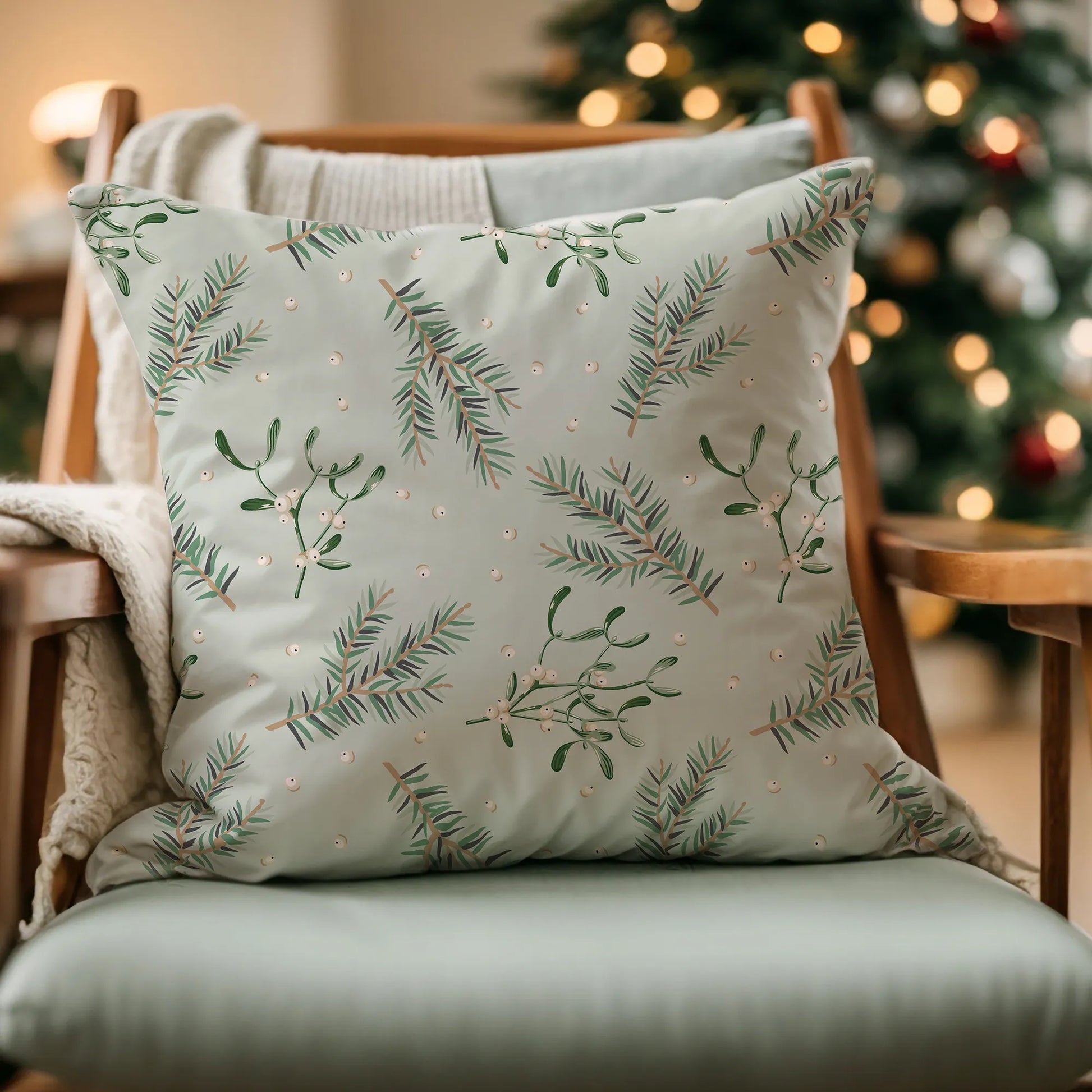 Mistletoe Christmas pillow on armchair with holiday lights – soft botanical decor for cozy seasonal styling