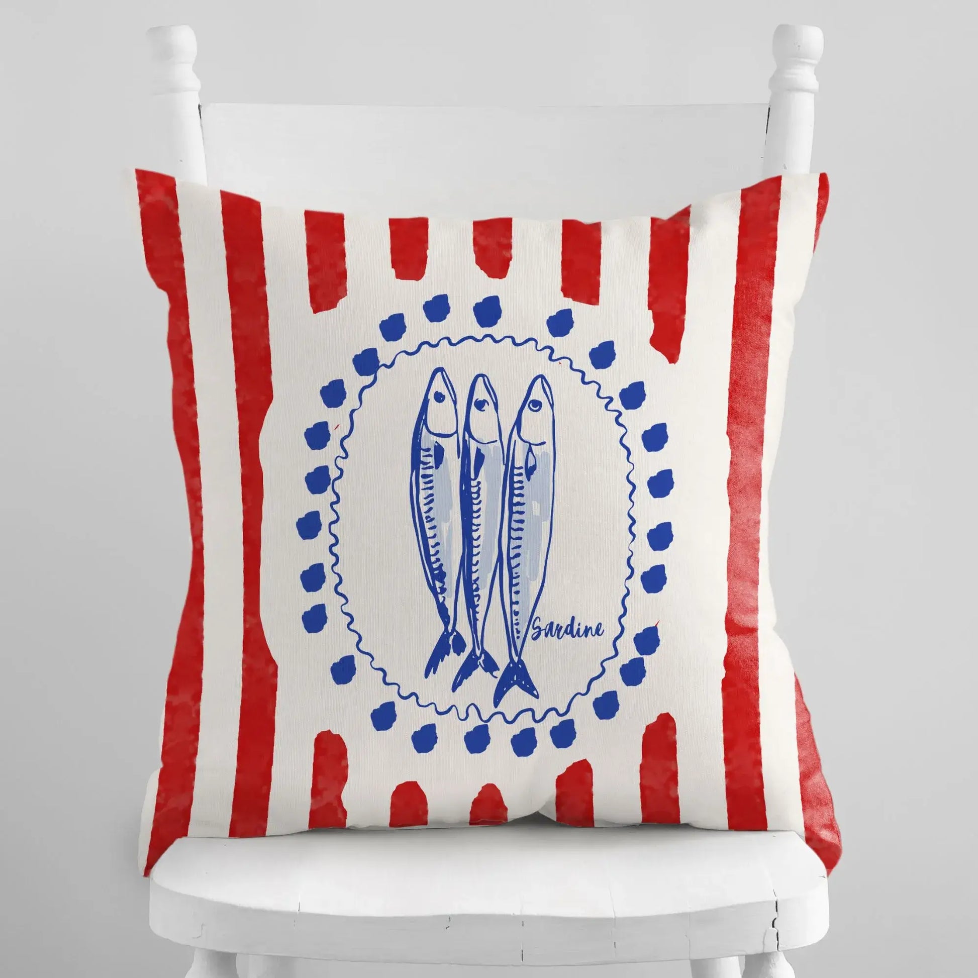 Sardine and Red Stripes Coastal Pillow and Cover on a white chair with red stripes and blue sardine illustrations.
