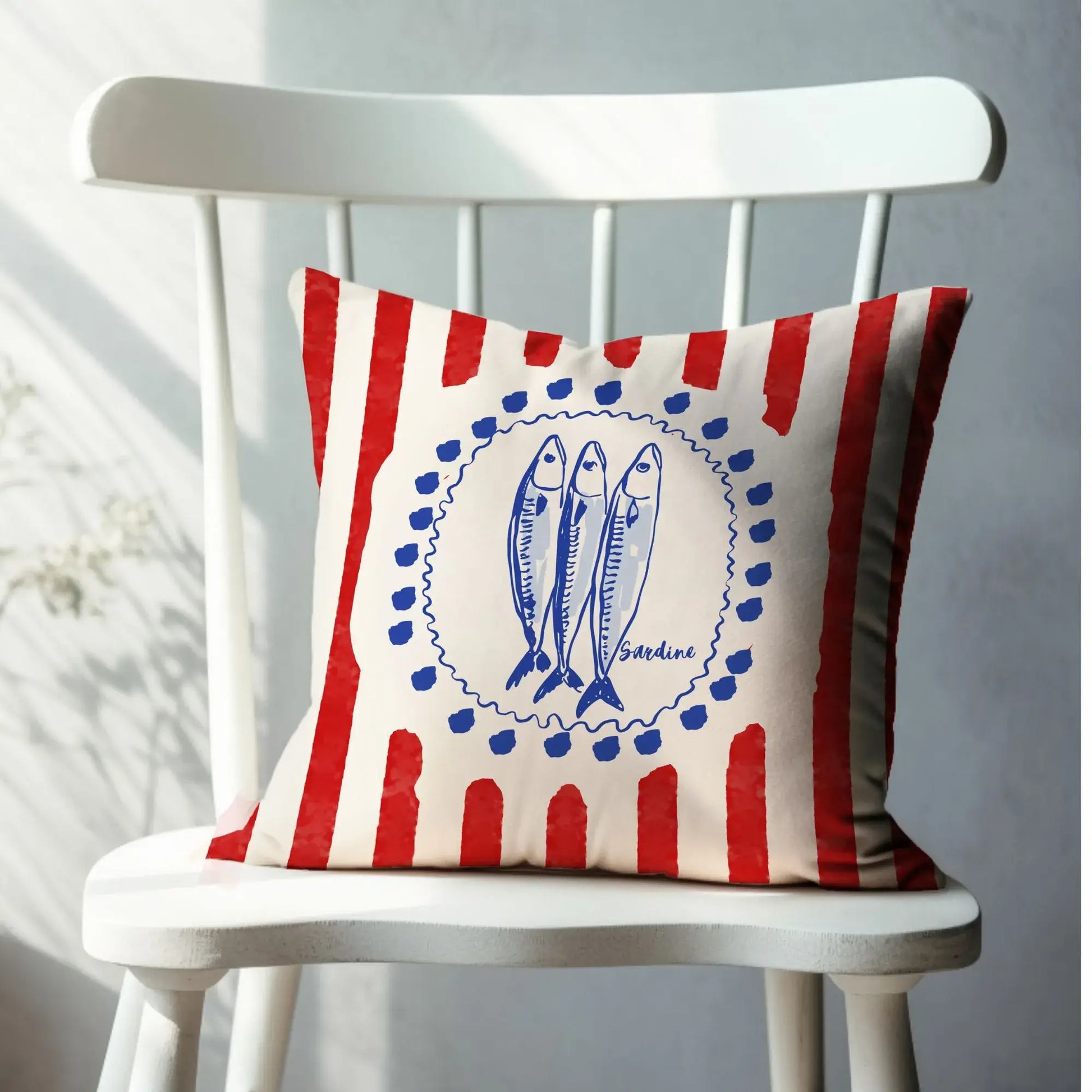 Sardine and Red Stripes Coastal Pillow and Cover with blue sardine illustrations and red stripes on a white chair.