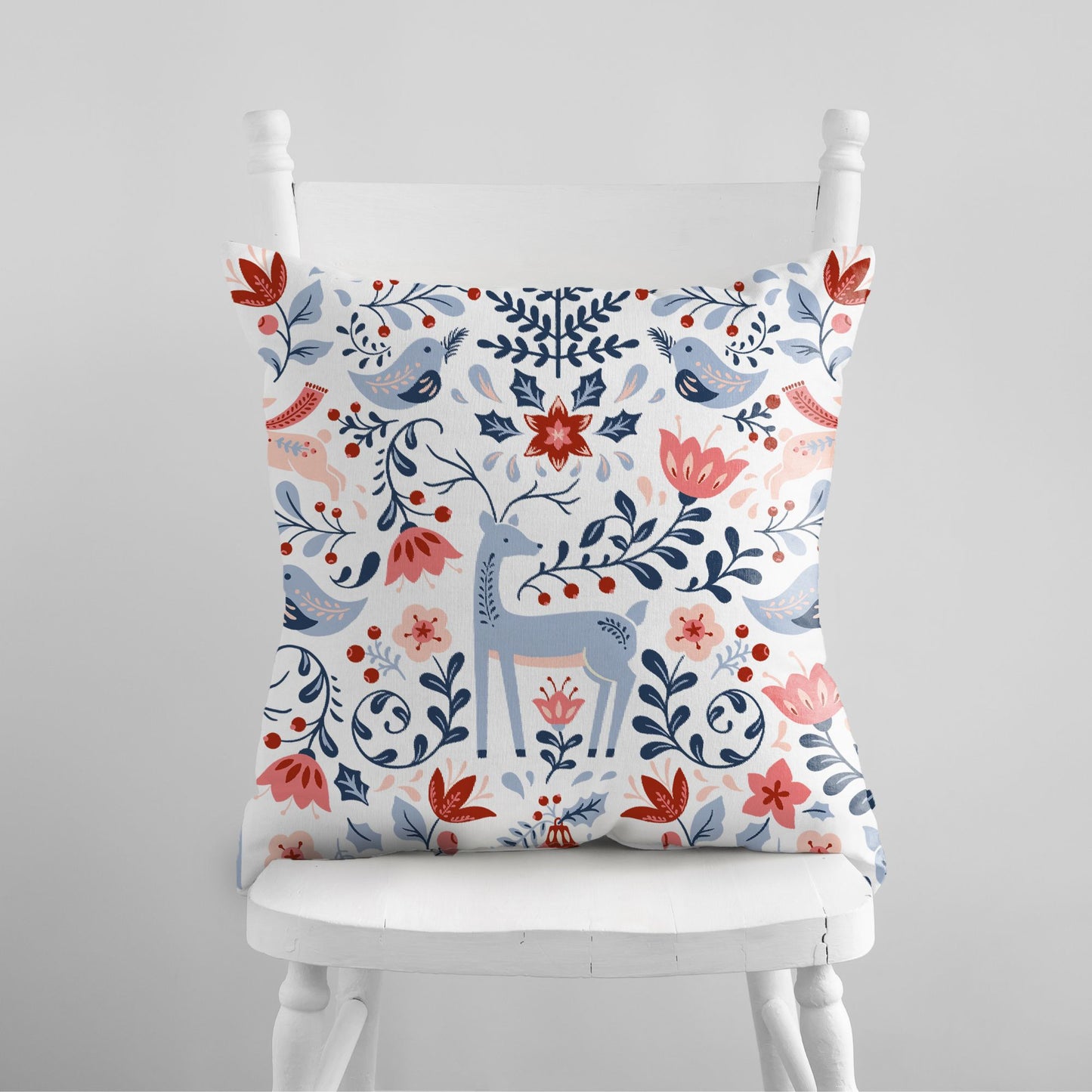 Nordic Reindeer Christmas Pillow featuring colorful floral and reindeer design on a chair.