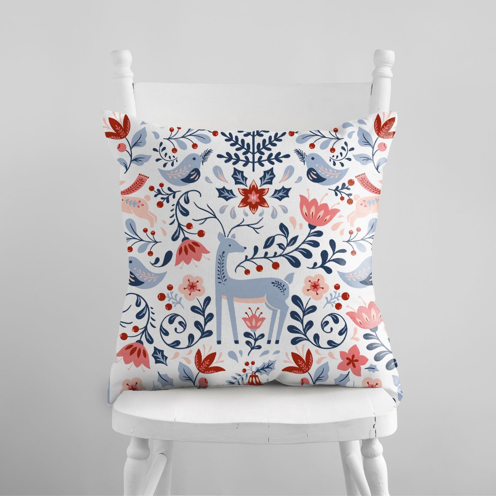 Nordic Reindeer Christmas Pillow featuring colorful floral and reindeer design on a chair.