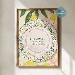 Framed watercolor quote art of a floral plate with lemons and the text “In summer, we slow down to taste the light.