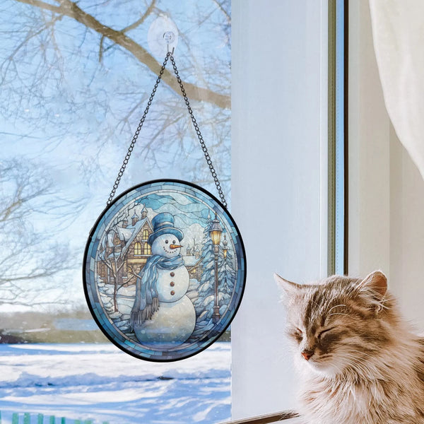 cat sitting next to window with snowman ornament on it