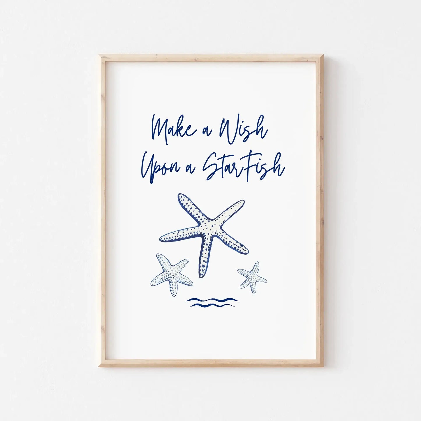Watercolor starfish printable art with "Make a Wish Upon a Starfish" quote in navy blue, displayed in a light wood frame.