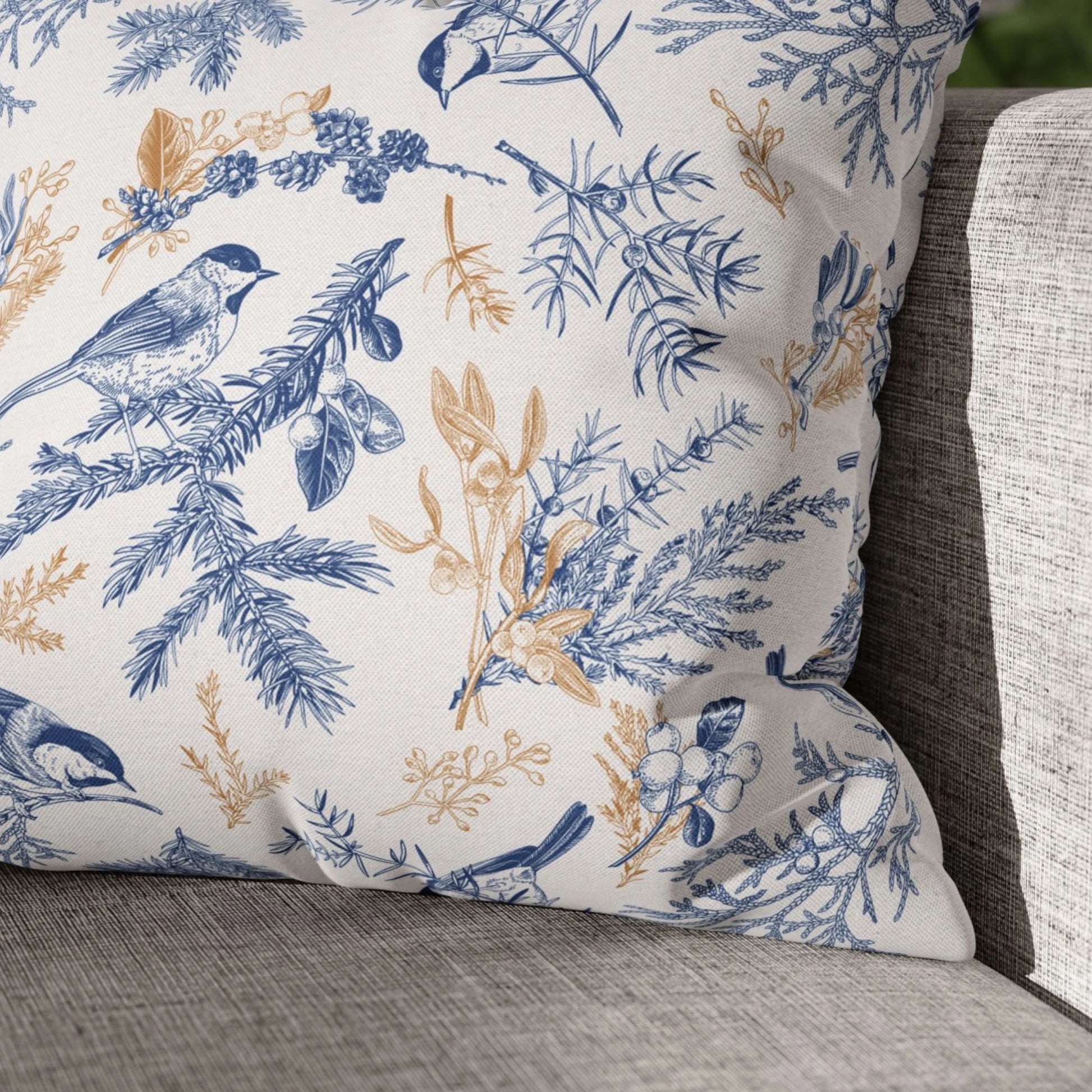 Close-up of vintage blue bird winter pillow with gold and blue botanical design on grey sofa