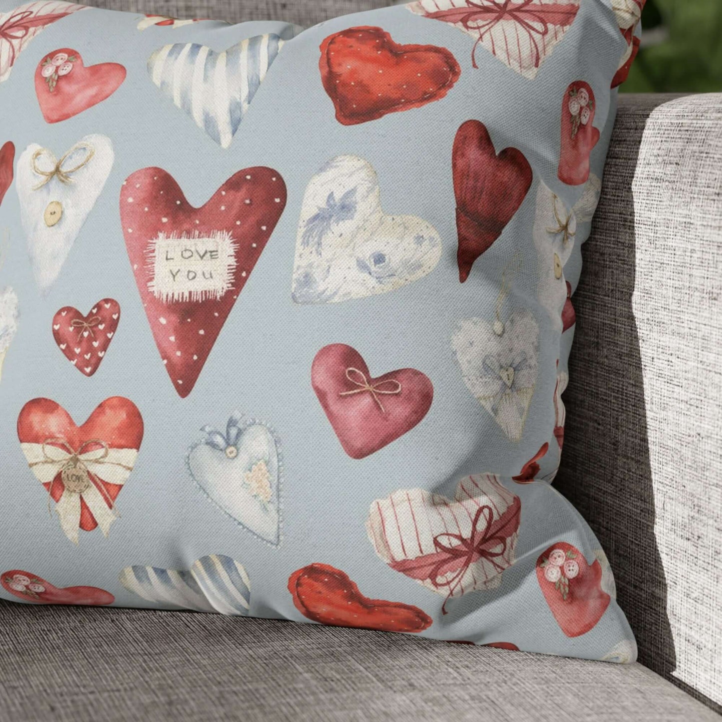 Vintage hearts Valentine pillow on a neutral sofa with watercolor red and blue hearts on blue fabric