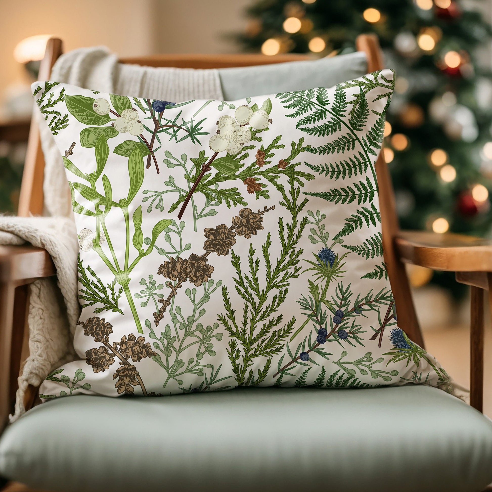 Vintage winter botanical pillow with green foliage and berries on chair in cozy living room with Christmas tree