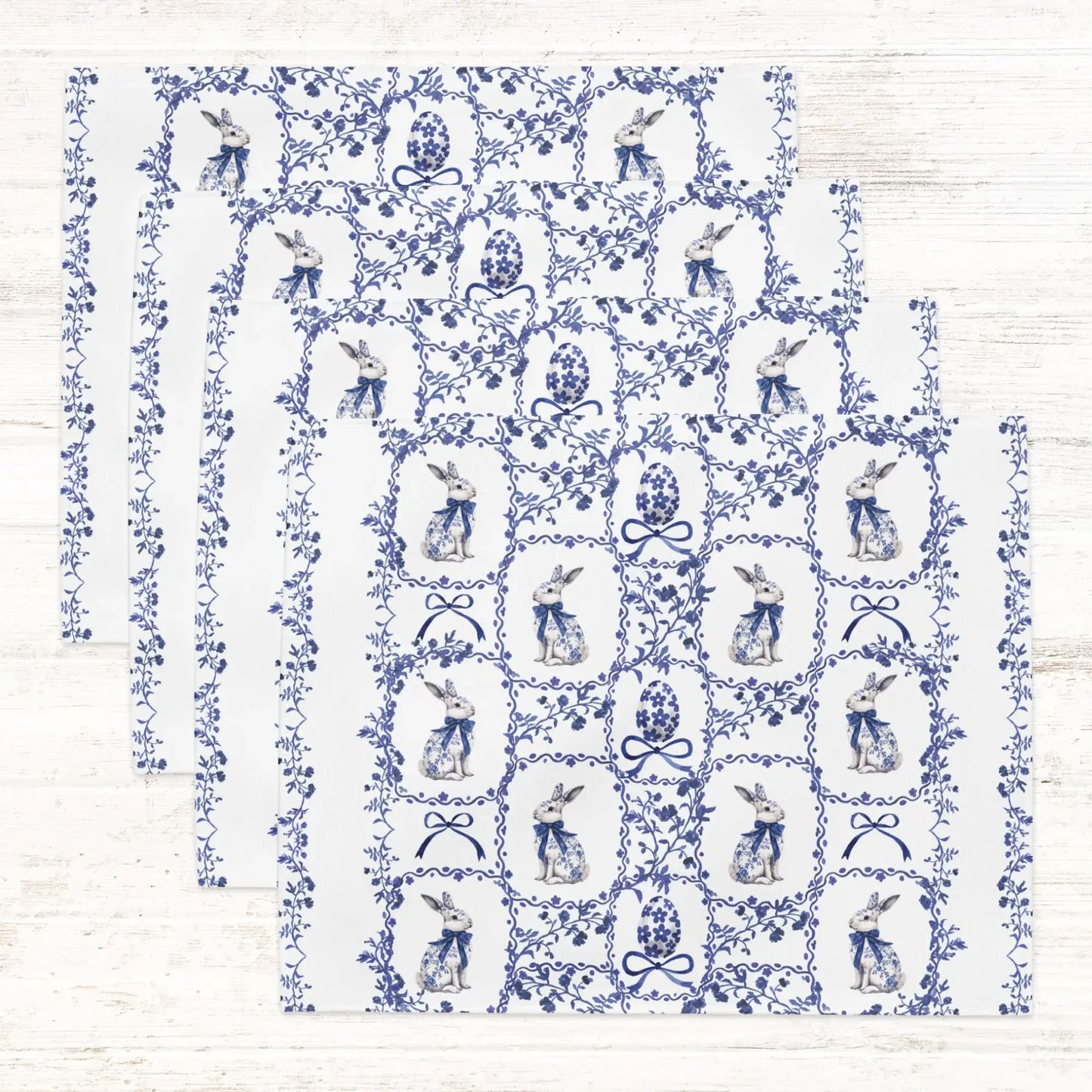 Set of white cotton placemats with a blue watercolor Chinoiserie pattern of rabbits, decorated Easter eggs, and delicate florals.