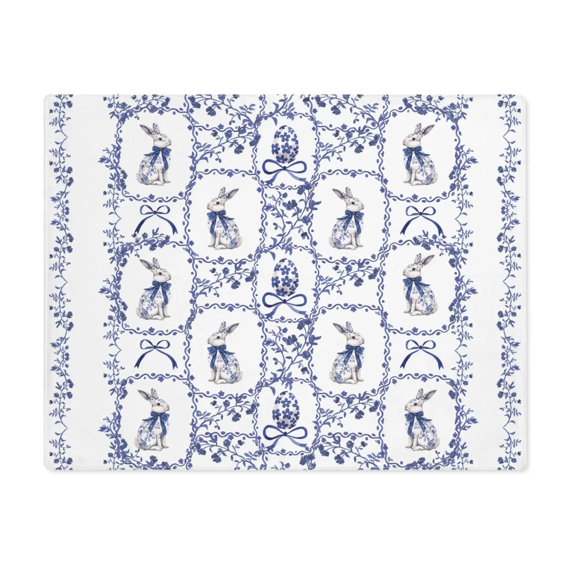 White cotton placemat with a blue watercolor Chinoiserie pattern of rabbits, Easter eggs, and delicate florals.