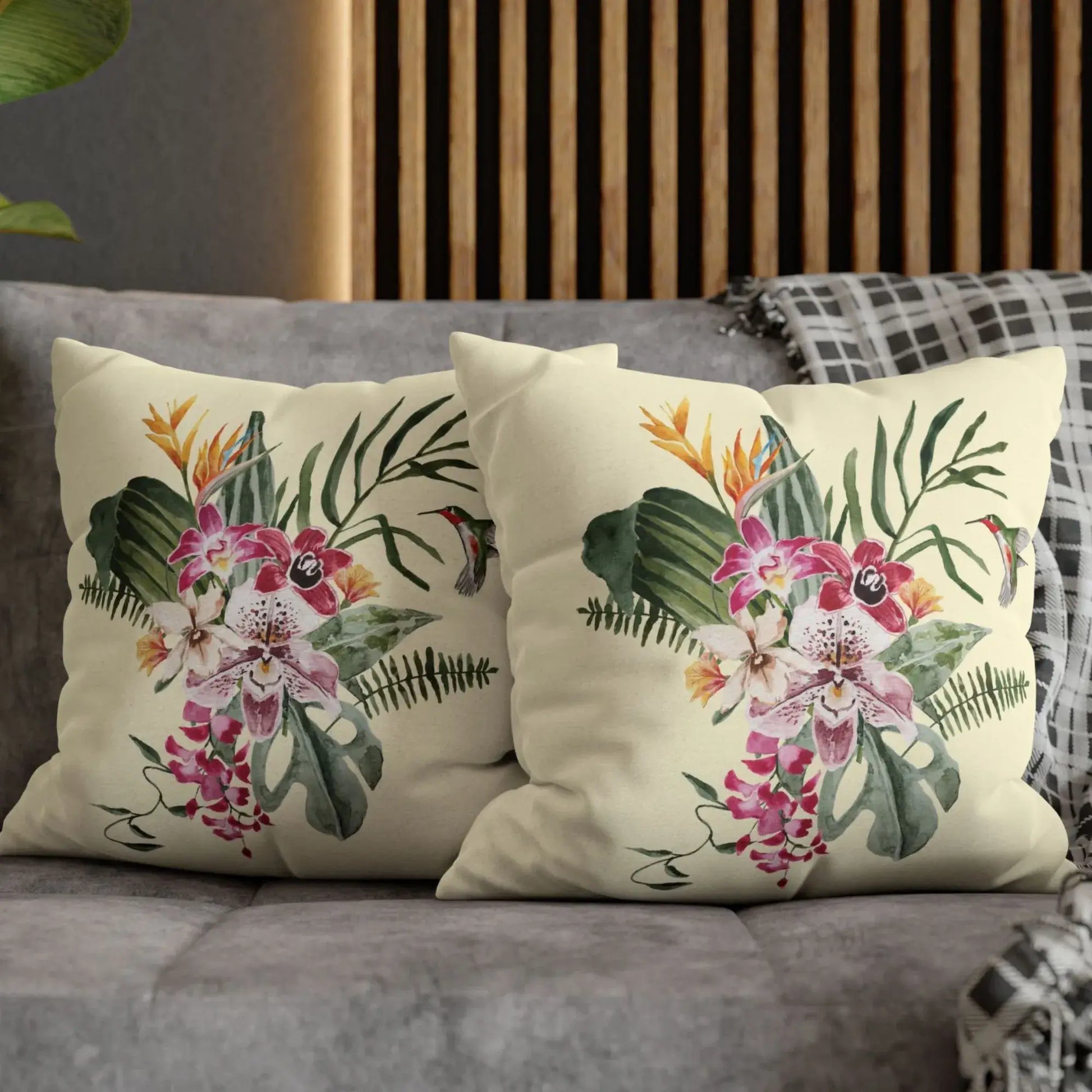 Watercolor Orchid & Hummingbird Pillow displayed on a couch with botanical design and vibrant tropical flowers.