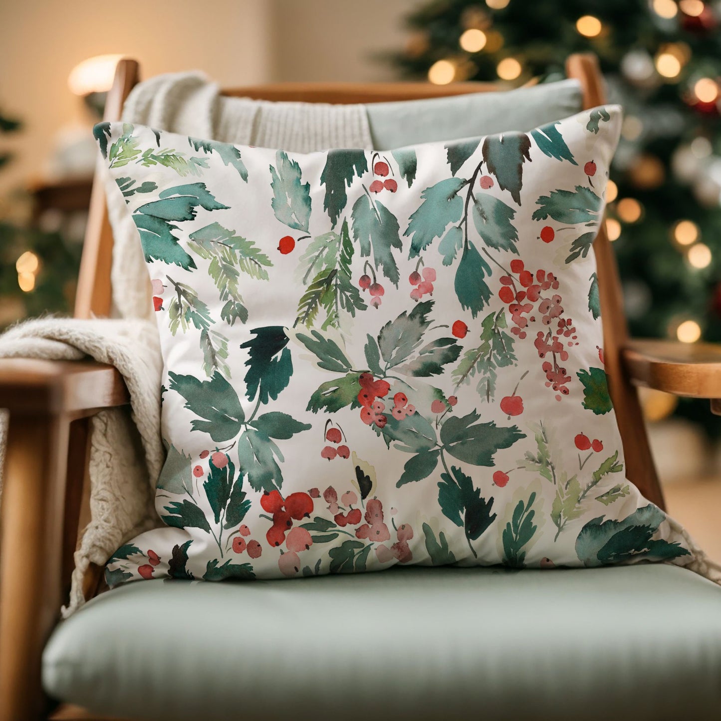 Watercolor Christmas pillow with red berries and green foliage on cozy chair – festive winter home decor