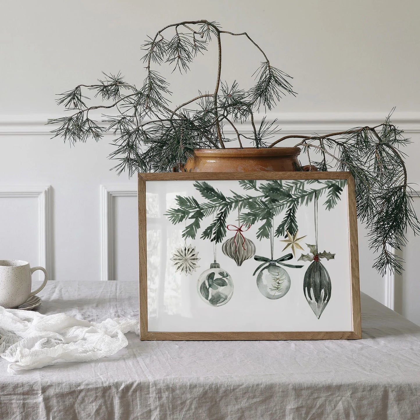 Watercolor Ornaments christmas print art displayed in a wooden frame with greenery, perfect for festive home decor.