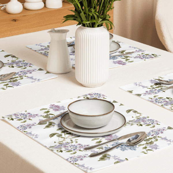 Watercolor Lilac Flower PLACEMAT Set on a dining table with a bowl, silverware, and a vase of greenery.