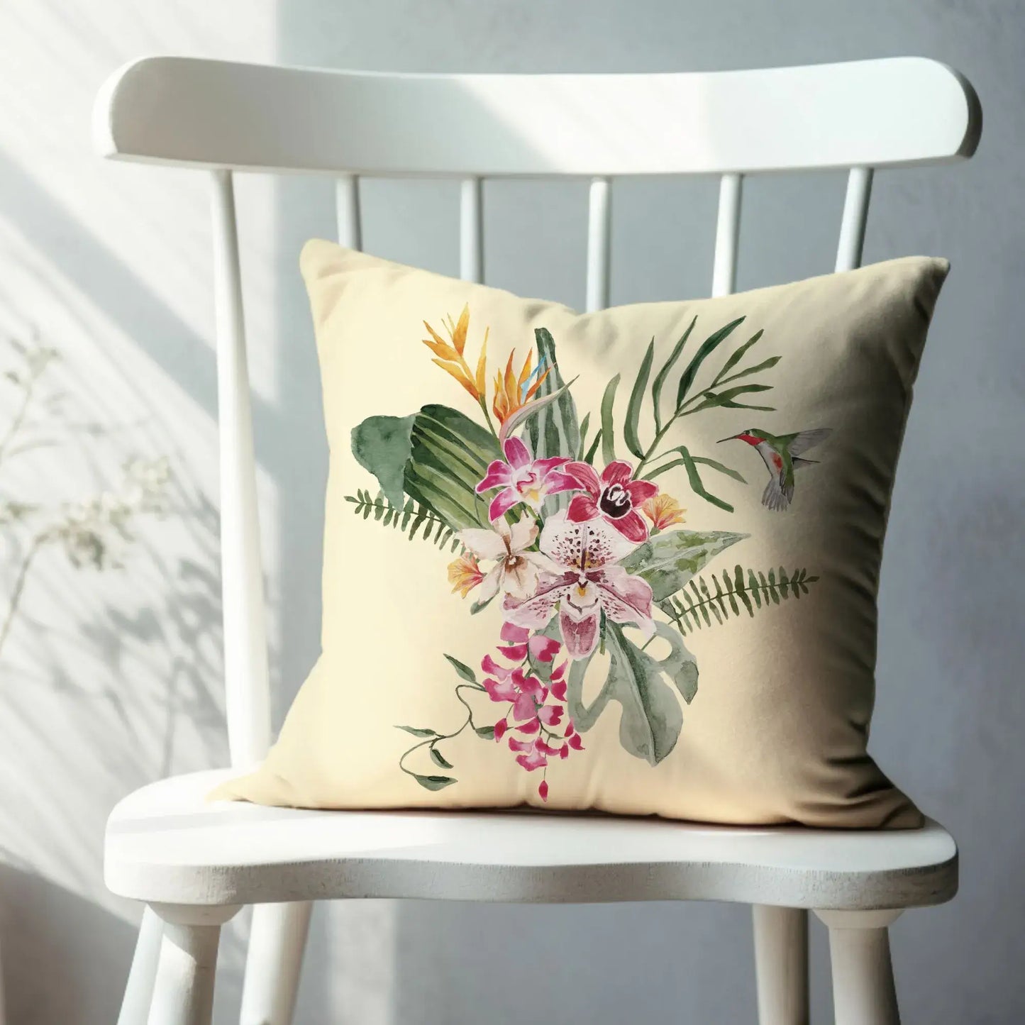 Watercolor Orchid & Hummingbird Pillow featuring a tropical floral design on a cozy chair.