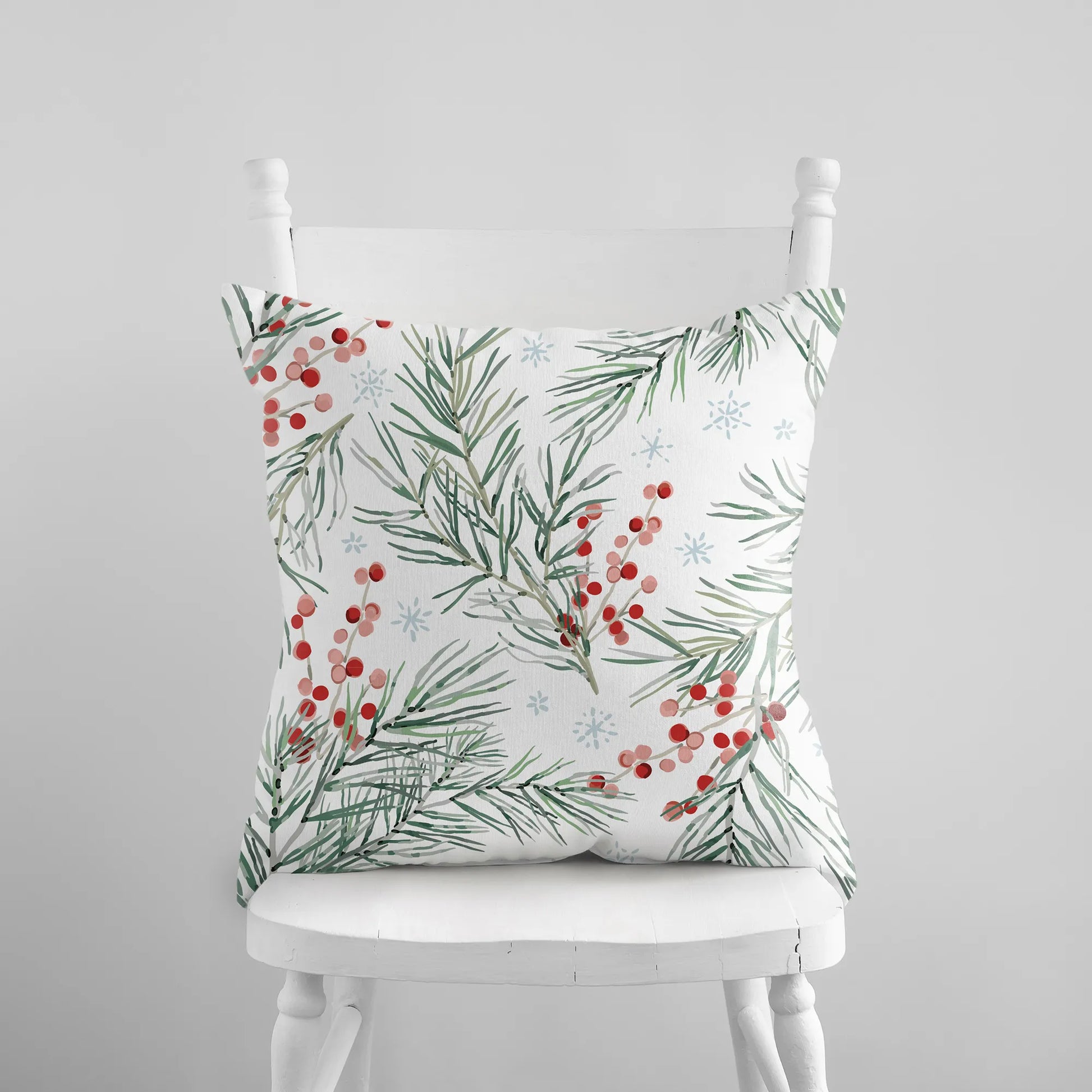 White pillow with watercolor pine branches, red berries, and snowflakes holiday cushion
