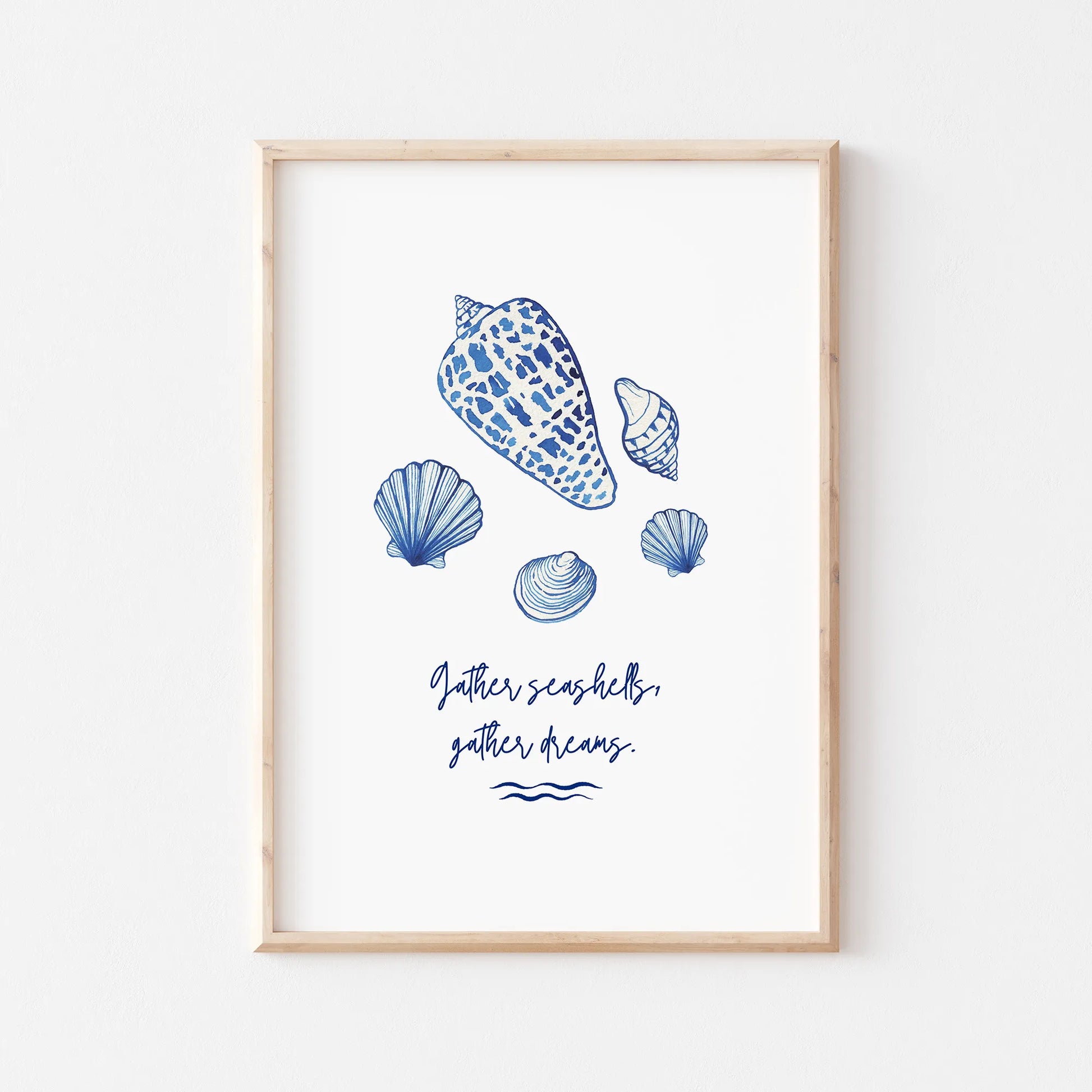 Minimalist watercolor seashell art print in natural wood frame, featuring coastal blue seashells and the quote "Gather seashells, gather dreams."
