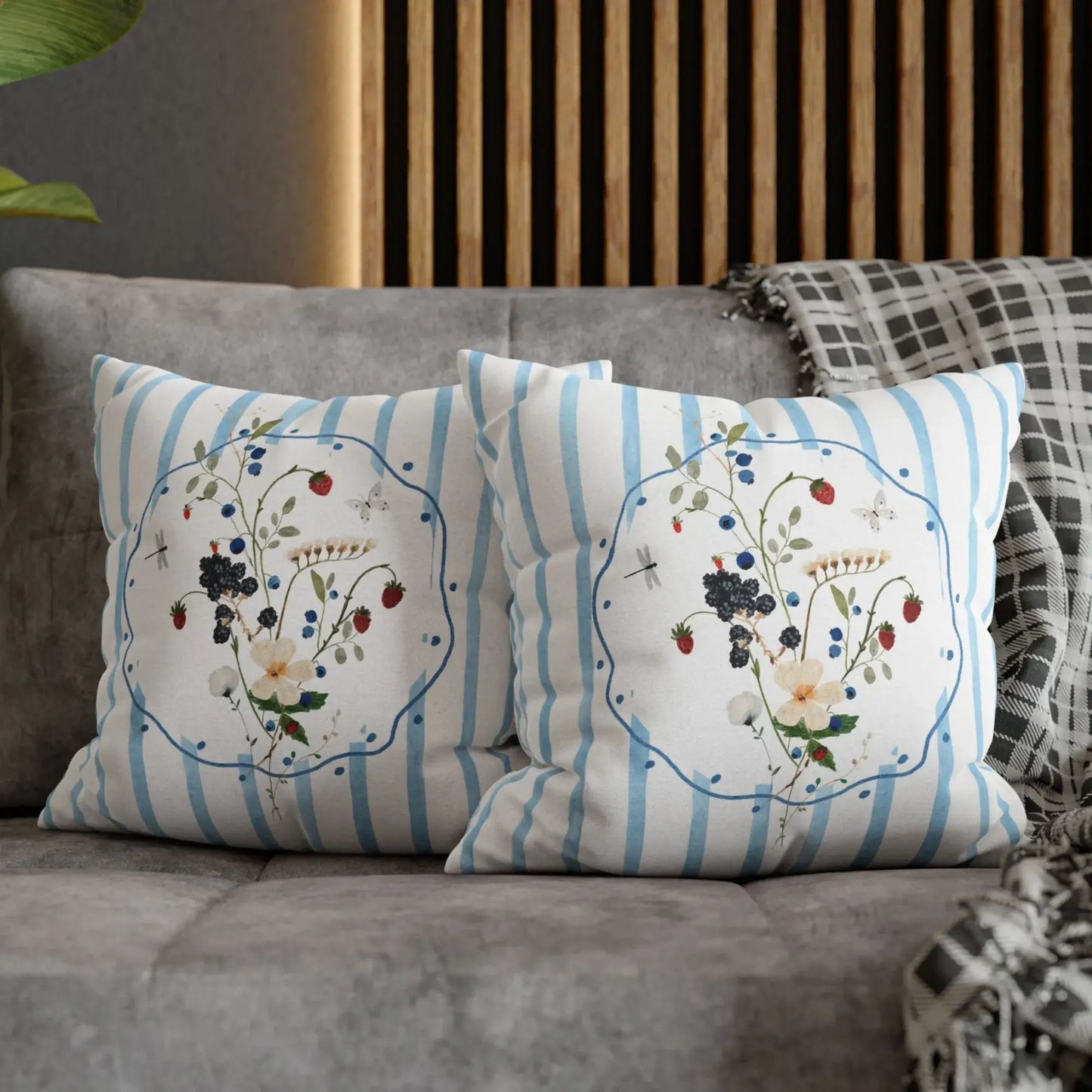 Watercolor Wildflower and Berry Pillow and Cover on a cozy sofa with blue stripes and floral motifs.
