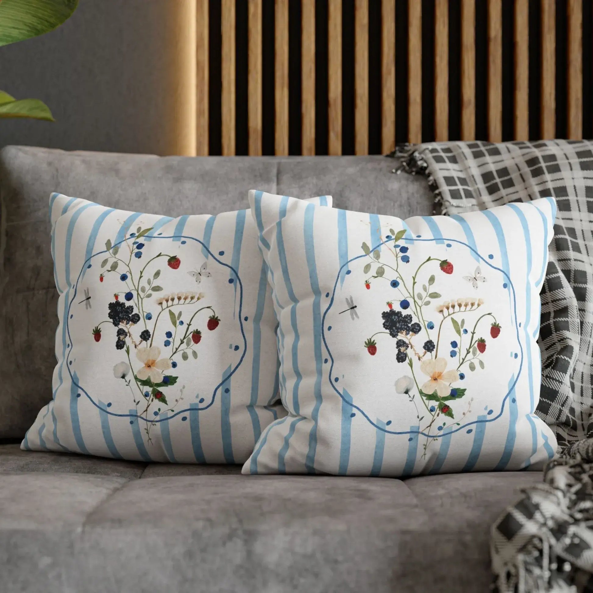 Watercolor Wildflower and Berry Pillow and Cover on a cozy sofa with blue stripes and floral motifs.