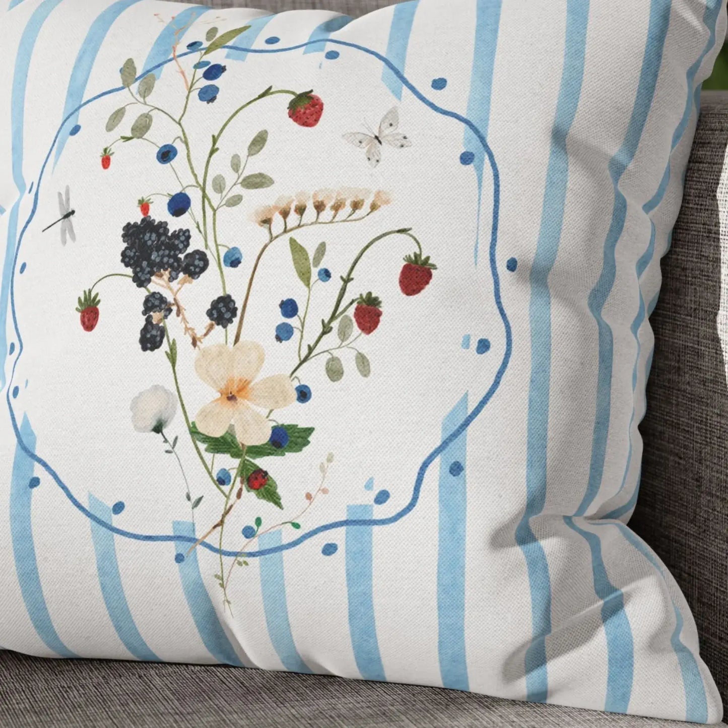 Watercolor Wildflower and Berry Pillow and Cover showcasing delicate wildflowers, berries, and blue stripes on a couch.