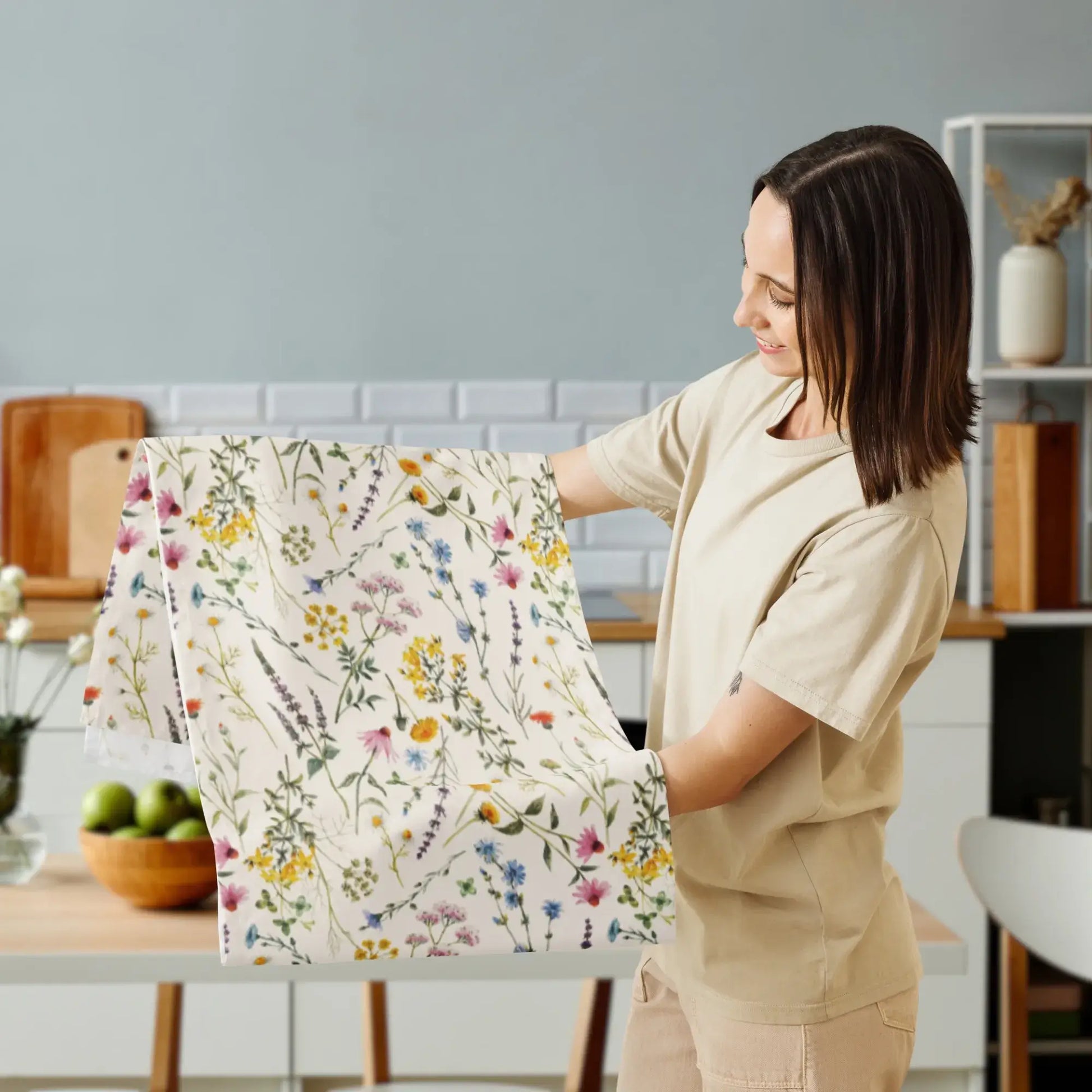 A woman proudly displaying the Watercolor Wildflowers Table Runner in a modern kitchen setting.