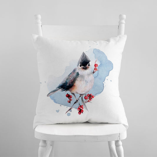 Watercolor winter bird pillow on white chair – soft seasonal decor with red berries and blue background