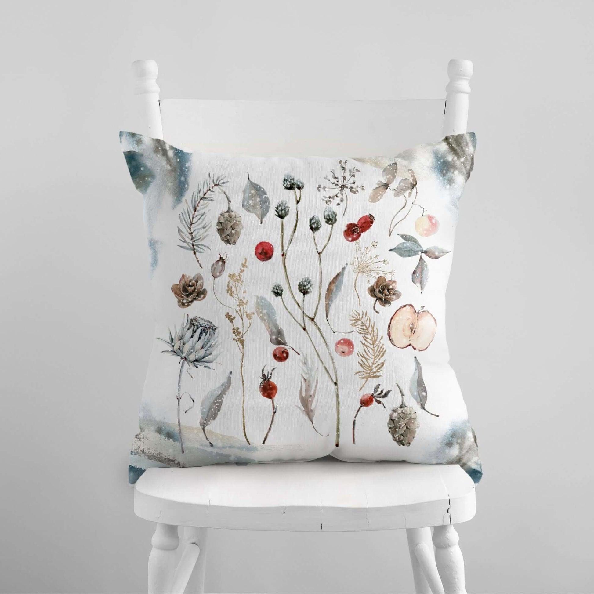 Winter Botanical Pillow Cover featuring watercolor winter plants, pinecones, and berries on a cozy chair.