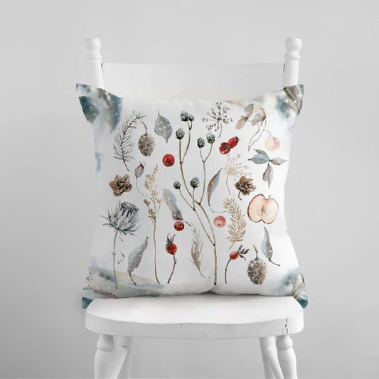 Winter Botanical Pillow Cover featuring watercolor winter plants, pinecones, and berries on a cozy chair.