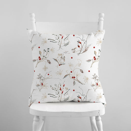 Watercolor winter botanical pillow with red berries on white chair – nature-inspired seasonal decor