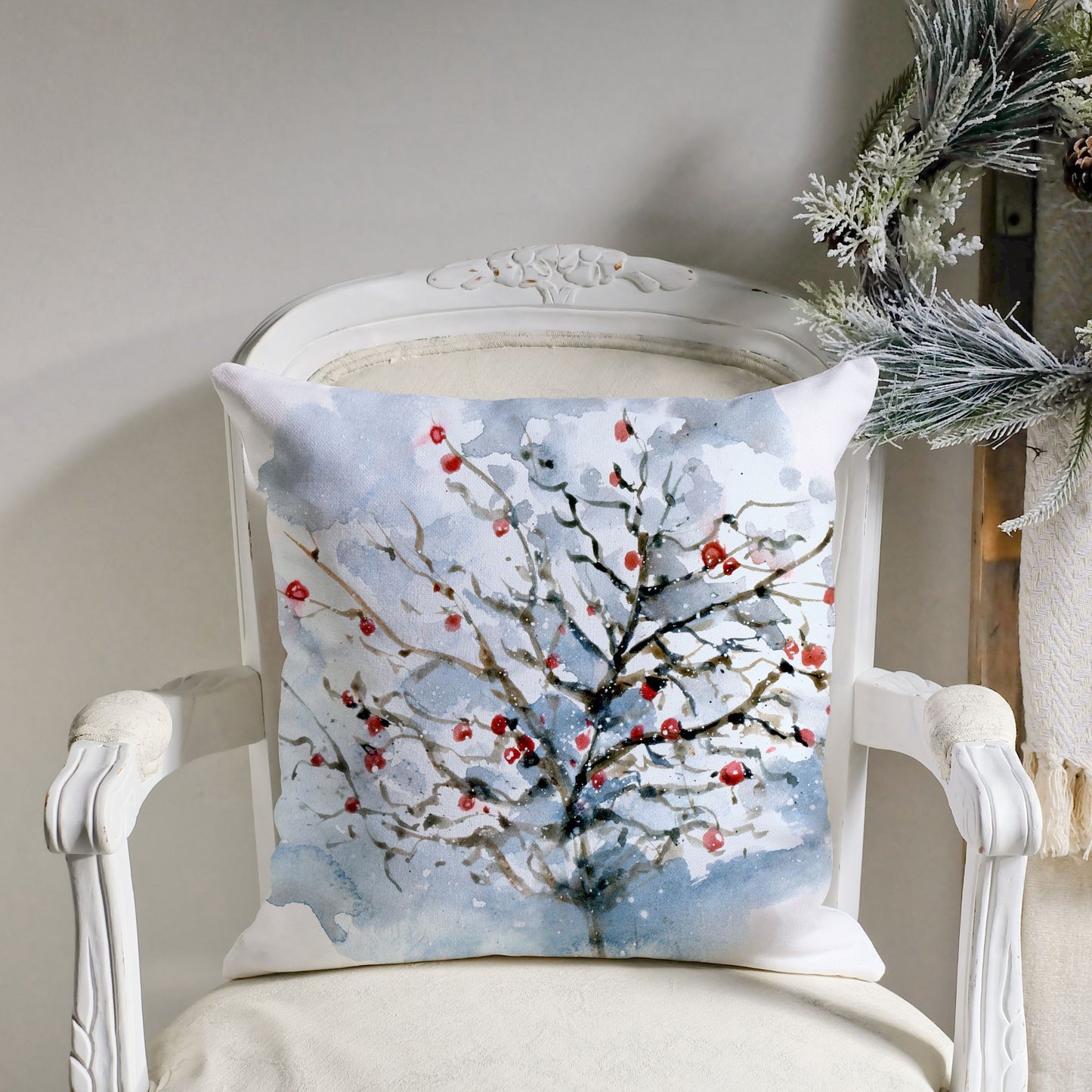 Watercolor winter pillow with snowy tree and red berries on white vintage chair – elegant Christmas decor setup