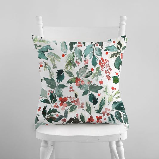 Watercolor Christmas pillow with red berries and spruce leaves styled on white couch – soft holiday decor

