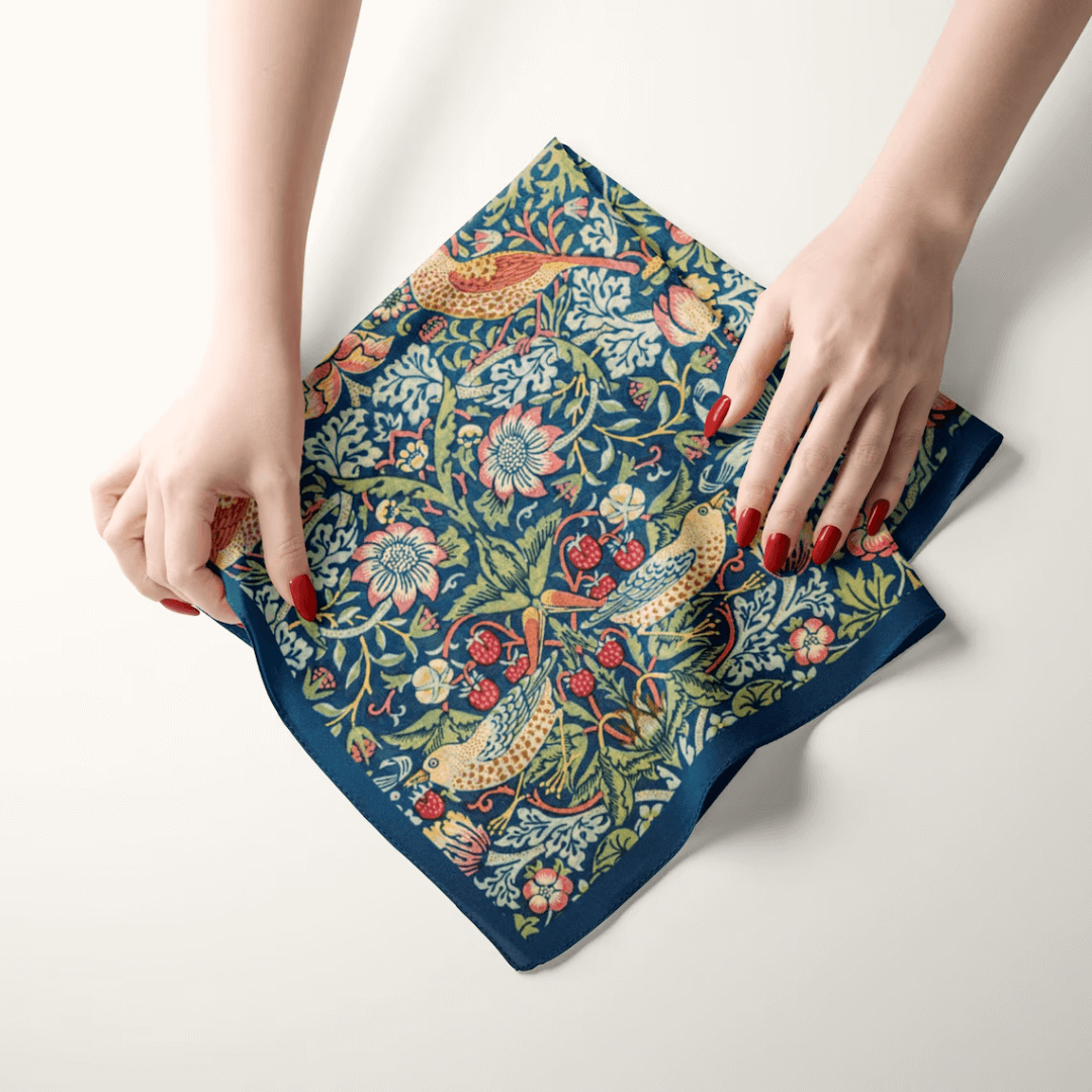 William Morris Strawberry Thief silk scarf held by hands, showcasing the intricate design of birds and berries.