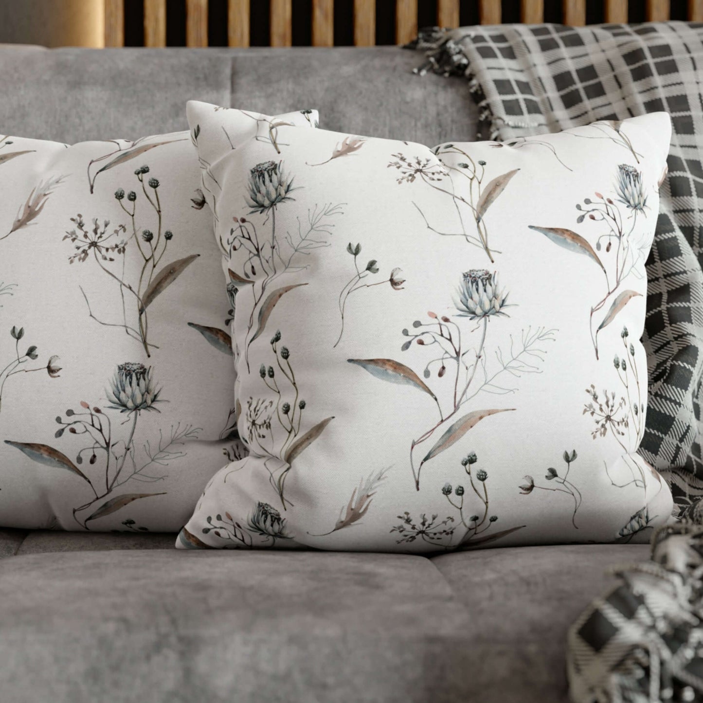 Winter botanical christmas pillow with delicate watercolor florals and soft greenery on a cozy sofa.